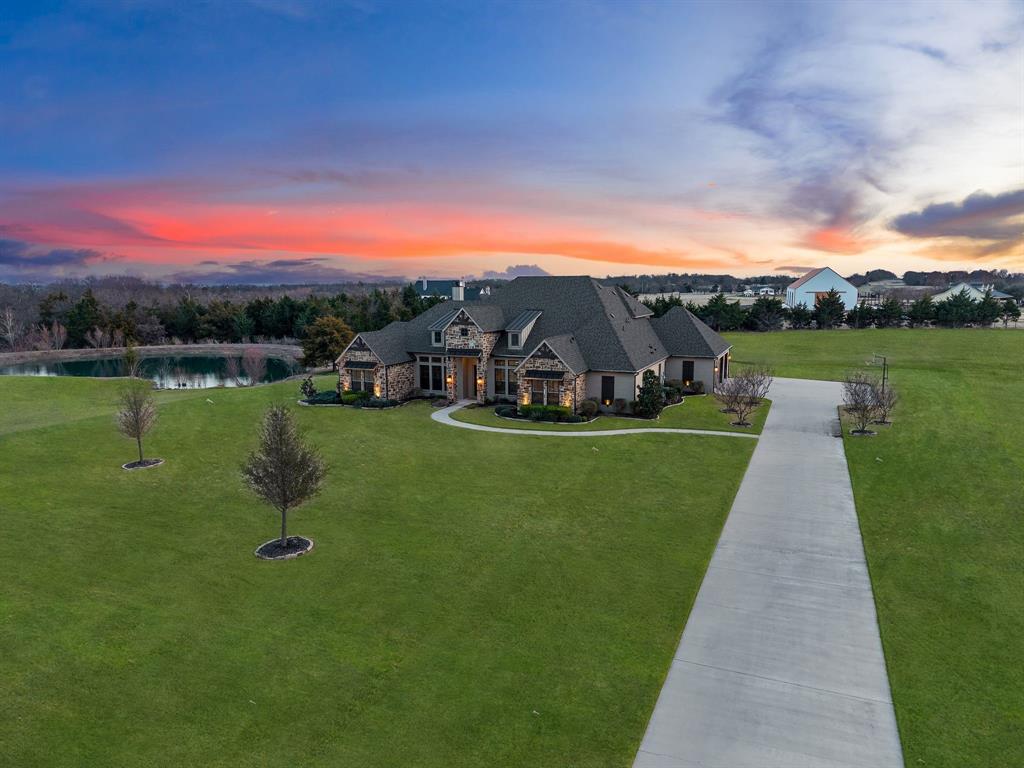 40K credit to buyer! This rare 6+ acre property in Celina with NO HOA, agricultural exemption with a low tax rate supported by an established beekeeping farm, private pond, and saltwater pool offers breathtaking sunset views and the freedom of country living in one of North Texas’ fastest-growing areas. Located in the sought-after Celina ISD, it offers peaceful country living while remaining conveniently close to the area’s growing amenities and conveniences. Built by Schramme Custom Homes, this 1.5-story home features the majority of its square footage on the main level, with only a spacious game room upstairs. Inside, the home features architectural details including brick accent arches and custom built-ins, along with a stunning stone fireplace accented with exposed wood beams. The gourmet kitchen showcases Taj Mahal countertops and backsplash, underlit cabinetry, spot-free gold faucets, a granite sink, and reverse osmosis drinking water. The entire home, including the cabinetry, has been freshly painted, and new hardwood floors flow throughout the first floor. The primary suite offers a spa-inspired bathroom with a soaking tub, separate shower, and dual vanities, while each bedroom connects to a bathroom, providing comfort and privacy. A flexible bonus room can serve as a playroom or home gym and a private study with built-ins provides an ideal work-from-home space. Upstairs, the game room features brand-new carpet and a wet bar, perfect for entertaining. Step outside to enjoy the extended covered patio with a built-in grill overlooking the saltwater pool and private stocked pond, creating the perfect setting for relaxing evenings or hosting gatherings. A convenient bathroom with patio access adds ease for poolside entertaining. Additional amenities include 50-amp RV hookups, upgraded electrical and AV systems, landscaping enhancements, and 3 refrigerators that convey. This property delivers the rare opportunity to enjoy acreage living with space and privacy.