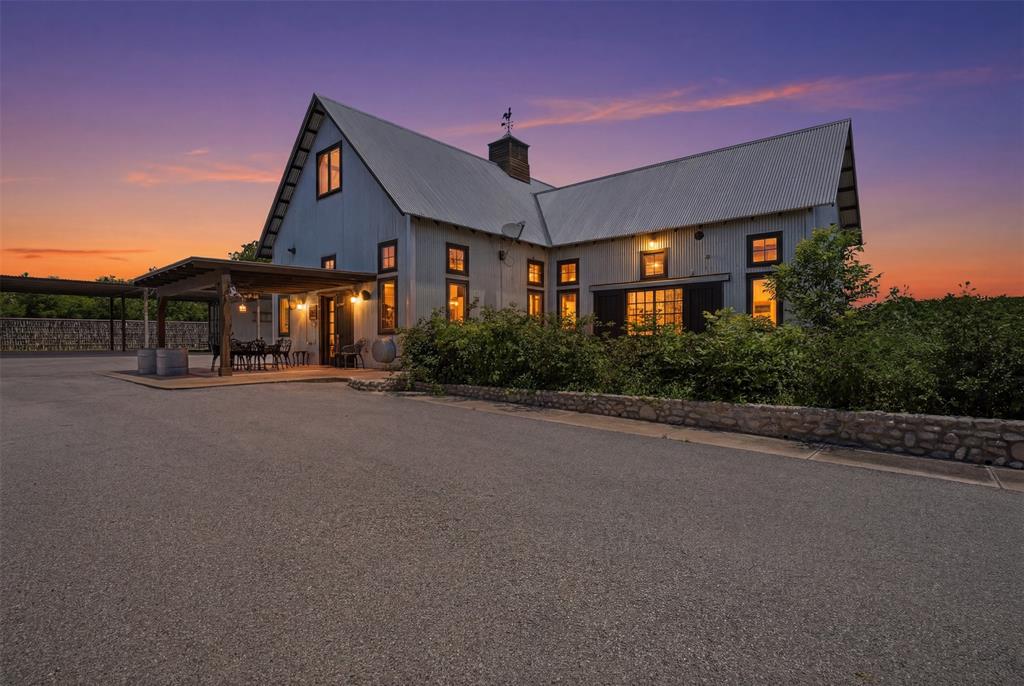 Welcome to ShaleRock Bluff, where peace, privacy, and purposeful country living come together on 5.45 breathtaking acres. As you enter the cedar tree-lined paved drive, a sense of serenity welcomes you home. Surrounded by natural beauty and thoughtfully designed for both relaxation and functionality, this one-of-a-kind property offers the ideal blend of modern farmhouse charm and ranch-style living. The 2,720 sqft primary residence features a warm traditional farmhouse feel with an open-concept layout, soaring vaulted ceilings, sliding doors that flood the home with natural light, and a rare traditional impluvium design element that creates a truly unique architectural experience. The spacious primary suite is conveniently located on the main floor, while secondary bedrooms upstairs provide privacy and flexibility for family or guests. The eat-in kitchen is complete with granite countertops, abundant cabinetry, and generous storage throughout. Step outside to experience a lifestyle unlike any other. The property is beautifully accented with sunflower gardens, expansive front and back porches, and endless Texas sunset views stretching across the bluff. Additional outdoor features include a greenhouse, ponds, shooting shed, workshop or shop, and an authentic ranch-style windmill connected to a 250-gallon passive gravity-fed water storage system. A custom cargotecture complete with a sauna, covered parking and storage container adds a modern rustic touch to this extraordinary retreat. Designed with versatility in mind, the property also includes 2 additional build sites with water and electric available, perfect for multi-generational living, guest homes, income-producing opportunities, or future expansion. Conveniently located and an easy commute to Fort Worth, this private Texas ranch retreat offers the rare opportunity to own a secluded slice of paradise while staying connected to city conveniences. Come experience the endless possibilities of ShaleRock Bluff today!