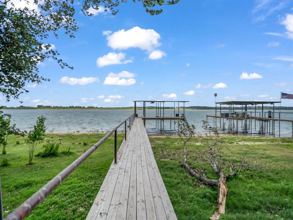 Tucked along the shores of Lake Weatherford, this cozy updated lake house offers the perfect blend of comfort, privacy, and waterfront living. Inside, you’ll find granite countertops, beautiful wood-look ceramic tile flooring throughout, and large picture windows in the living room that frame stunning lake views and fill the home with natural light.

The spacious primary suite provides a relaxing retreat, while the secondary bedroom makes a perfect guest room or home office. The updated bathroom features a walk-in shower and space for a stackable washer and dryer. An all-in-one washer-dryer unit and refrigerator are negotiable with an acceptable offer.

Step outside to enjoy mature trees, thoughtful landscaping, and a spacious dock ideal for entertaining, relaxing by the water, or watching the nearby 4th of July celebrations. The dock is already equipped with electricity and ready for your future boat lift. A privacy fence and electric gate create a secluded feel from the road, while the generous parking area offers plenty of room for guests and gatherings.

Whether you’re looking for a weekend getaway, investment opportunity, or full-time waterfront escape, this charming lakefront property is ready to enjoy.