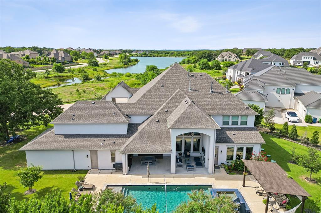 Welcome to a multigenerational home in the desirable Townlake community in Flower Mound, situated on a premium lake-facing lot at a quiet cul-de-sac. Set on 0.8 acres, this property offers generous outdoor space for activities, pets, and entertaining. An inviting front porch leads to a grand foyer with dual staircases and a private office with french doors. The open floor plan blends traditional and contemporary elements, offering abundant natural light, clean lines, and sliding glass door for seamless indoor-outdoor living. The kitchen features a quartzite island, premium built-in appliances, and a butler’s pantry. The spacious primary suite is a private retreat with spa-inspired bath, stand-alone soaking tub, walk-in shower, and his-and-hers closets. A guest quarters features its own entrance, living area, and kitchenette—creating an ideal retreat for extended family, long-term guests, or live-in support while maintaining complete privacy from the main home. Upstairs offers three ensuite bedrooms with walk-in closets, a game room, stadium sitting media room and a covered balcony overlooking the lake. The backyard is a resort-style escape with a custom Robertson’s salt water sparkling pool & spa, covered patio with fireplace, pergola, and centennial native oaks. A porte-cochère leads to a private motor court and four-car garage. New roof. Conveniently located near award-winning schools and DFW Airport.