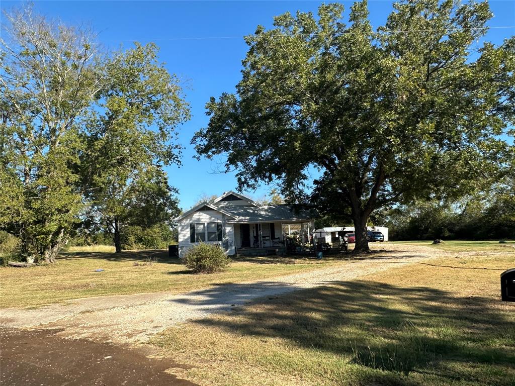 Escape to the Country - Farmhouse on a Quiet Country Road. Enjoy the evening breeze on your covered front porch shaded by large producing pecan trees. Step inside to a large living and dining area with plenty of room to enjoy family time. Retire for the night in 4 bedrooms with closets. The 4th bedroom or flex room is a converted back porch with exterior door to a covered carport or patio area. This room also has an ensuite full bathroom and the utility area for washer and dryer. The front bedroom has 2 closets. There is a kitchen in the center of the house with a double oven, microwave with vent, dishwasher, large farmhouse sink, refrigerator, original wood cabinets, and renovated granite countertops and tile backsplash. Outside there is plenty of privacy with 1.6 acres, a small pond in the back corner of the property, 2 chicken coups, fenced garden area, 2 car garage, and storage building. There is even a pad and electric hookup in place for an RV or tiny home. With a separate electric meter and sewage hookup this space could be rented for extra income. The septic system, plumbing, electrical and the HVAC are new.