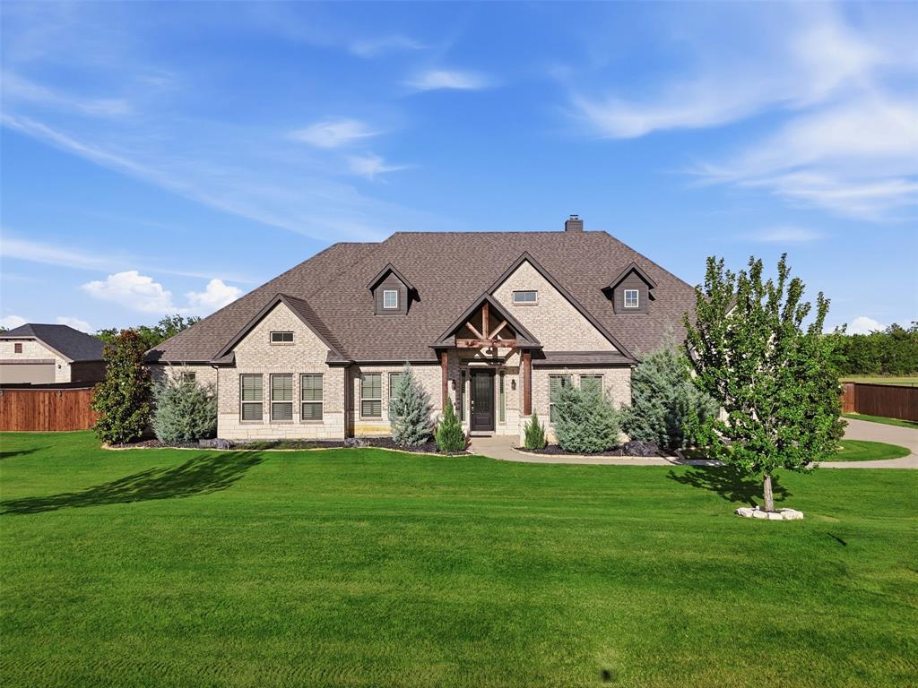 Vacant and ready for a new owner! Discover country serenity in this magnificent 4-bedroom, 3.5-bathroom traditional stone and brick home, with NO city taxes! Situated on a 1.03-acre lot in beautiful Summit Estates, this 3,481 sq. ft. home offers country living just outside the city limits. No MUD, no PID. This home features wood flooring, crown molding, and high-end finishes throughout. There are two living areas and two dining areas with large windows for natural light. Windows are covered with plantation shutters or remote controlled blinds. The main living area, with its wood-burning fireplace, flows seamlessly into the gourmet kitchen that includes granite countertops, a large central island, custom built-in cabinets, and a walk-in pantry. The primary bedroom is a private sanctuary featuring a tray ceiling, dual vanities, a separate walk-in shower, and a walk-in closet.  This home offers a formal dining room, a dedicated home office, and a spacious family or media room perfect for entertaining. One of the secondary bedrooms also has an ensuite, perfect for guests! The other two bedrooms share a hall bath.
The outside is perfect for outdoor living and hobbies. Enjoy a landscaped front yard and a massive backyard featuring a three-tiered extended covered patio with a fire pit and grilling area. In the back yard are multiple fruit trees all with irrigation drips, as well as blackberries, blueberries and grapes. A 16 station sprinkler system takes care of the front and back yards. The 736 square foot detached workshop with electric, including 220V, also has 30 and 50 amp service. Another 50 amp outlet is outside the shop for your RV or generator hookup. The shop has one double roll up door, one single roll up door, and a side walk through door.