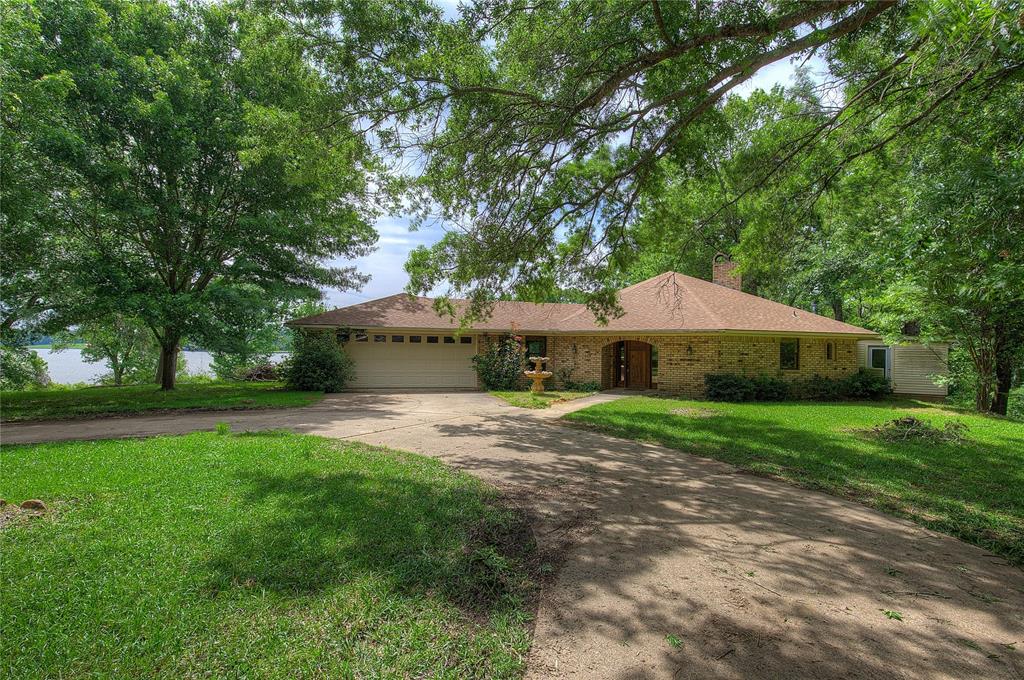 Discover a rare opportunity to own a 6.10-acre waterfront estate on the pristine shores of Lake Cypress Springs. This solid brick home offers over 678 feet of expansive water frontage, providing breathtaking lake views from every main living area. The heart of the home is an open-concept living room featuring soaring vaulted ceilings, rich natural woodwork, and a cozy fireplace. The adjacent kitchen has been thoughtfully updated with classic wood cabinetry and granite countertops, flowing seamlessly into a bright breakfast area and a dedicated space for a large dining table—perfect for hosting family gatherings. 
The private primary suite serves as a true retreat, complete with its own fireplace for chilly evenings and a unique, dedicated hot tub room just steps away. Two additional bedrooms and a second full bath provide ample space for guests. Functional versatility abounds with an attached two-car garage; half of this space currently serves as a craft room or home office but can easily be restored to full garage use if desired. Outdoor living is a highlight, featuring a peaceful screened-in porch and a sunroom to soak in the scenery year-round. 
Beyond the main residence, the property includes a detached two-car garage and workshop, along with a dedicated RV cover for your adventure vehicles. While the home requires some TLC—including fresh paint, new flooring, and repairs to the wood deck and dock—it presents a blank canvas to create your dream lakefront sanctuary. With no HOA restrictions and the potential to further enhance the views by clearing select property lines, this expansive lot offers unmatched privacy and endless potential on one of Texas's most beautiful lakes.

This property is leasehold and under the jurisdiction of the Franklin County Water District.   www.fcwd.com