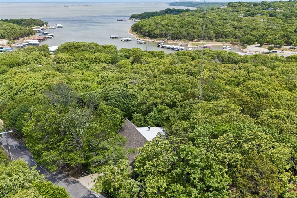 Enjoy scenic views of Lake Texoma from this spacious 2,956 sq ft FULLY furnished home in Pottsboro, ideally situated on four lots offering added space, flexibility, and privacy. This well-designed property features 5 bedrooms and 3 bathrooms, including two primary suites, making it well-suited for full-time living, a second home or investment opportunity. Each primary suite includes an ensuite bath and walk-in closet. One primary bath has been recently remodeled and features a walk-in shower with steam feature. The second primary suite offers a jetted garden tub, separate vanities, and a private refrigerator for added convenience and comfort, creating ideal accommodations for owners and guest. The interior showcases hardwood floors, vaulted ceilings, and an open-concept layout that provides a functional flow for everyday living and entertaining. The kitchen is equipped with an island, breakfast bar and opens to the dinning area, where window frame views of the lake. The family room features a wood-burning fireplace, creating a comfortable gathering space. Additional living areas include a sunroom filled with natural light and a loft with a reading nook, offering flexible space for a home office, game room or guest accommodations. outdoor living is enhanced by a covered deck with teak wood flooring, providing a space to enjoy the surrounding setting and lake views. The four-lot configuration allows for expanded outdoor use, additional parking, or future improvements, subject to local regulations. Property features include 3 HVAC systems, two recently replaced water heaters, a water softener, and generous storage throughout the home. This property presents strong potential as a short term or long term rental investment, second home, or primary residence. Buyer to verify all local regulations, usage and rental restrictions. BOAT DOCK available for separate purchase, buyer to verify availability, permitting, and details. Voluntary HOA; Buyer to verify.