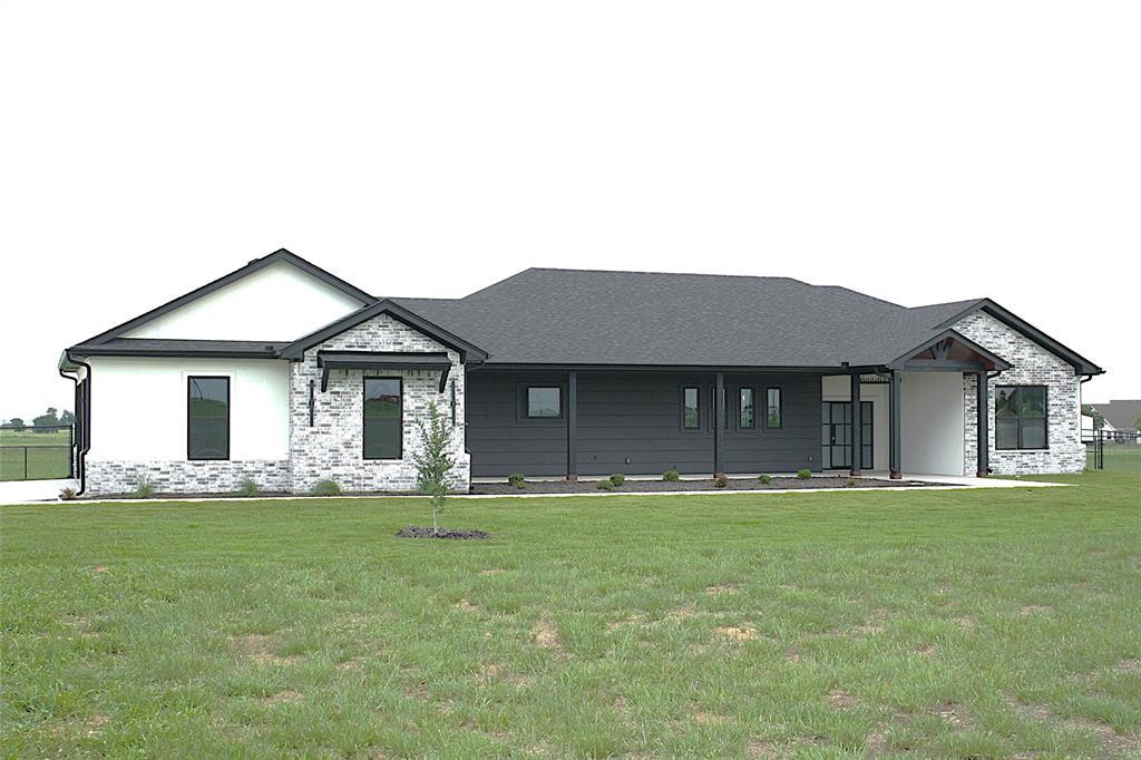 This stunning 4-bedroom, 3.5-bath, 3-car garage home with 2,602 sq ft offers a thoughtfully designed split floor plan and sits on 6.581 peaceful acres in the desirable Willow Moon Ranch subdivision. This property showcases exceptional craftsmanship, energy efficiency, and modern style. Energy efficiency begins with spray foam insulation, making the home extremely efficient year-round. The interior features quartz countertops, custom wood cabinetry, stainless steel appliances including a refrigerator, luxury vinyl plank flooring, ceiling fans in all bedrooms and the living room, and 30-year dimensional shingles. The home also includes a sprinkler system and front and backyard sod. The spacious living and dining area features a stunning beamed cathedral ceiling, abundant natural light, and a multifunction electric fireplace accented with beautiful wood details. The dream kitchen offers generous quartz counter space, double ovens, an abundance of custom cabinetry, a large island, and a breakfast bar with convenient pop-up electrical outlets. Additional highlights include an extra-large pantry with additional storage and workspace, plus a coffee bar with wine cooler. The expansive primary suite features dual vanities, a dedicated make-up nook, a massive walk-in closet, a freestanding soaking tub, and a beautiful tiled walk-in shower. The well-designed laundry room includes custom wood cabinetry, a sink, coat hooks, shoe storage, and quartz countertops for added convenience. One guest bedroom includes a private ensuite bathroom, while the other two bedrooms share a Jack-and-Jill bath, and all bedrooms feature walk-in closets. The oversized three-car garage offers additional storage space. Outdoor living is just as impressive, featuring a large, covered patio with a beautiful wood-burning fireplace and large, covered kitchen complete with a sink. The expansive acreage provides endless possibilities for family recreation, relaxation, and enjoying country living.