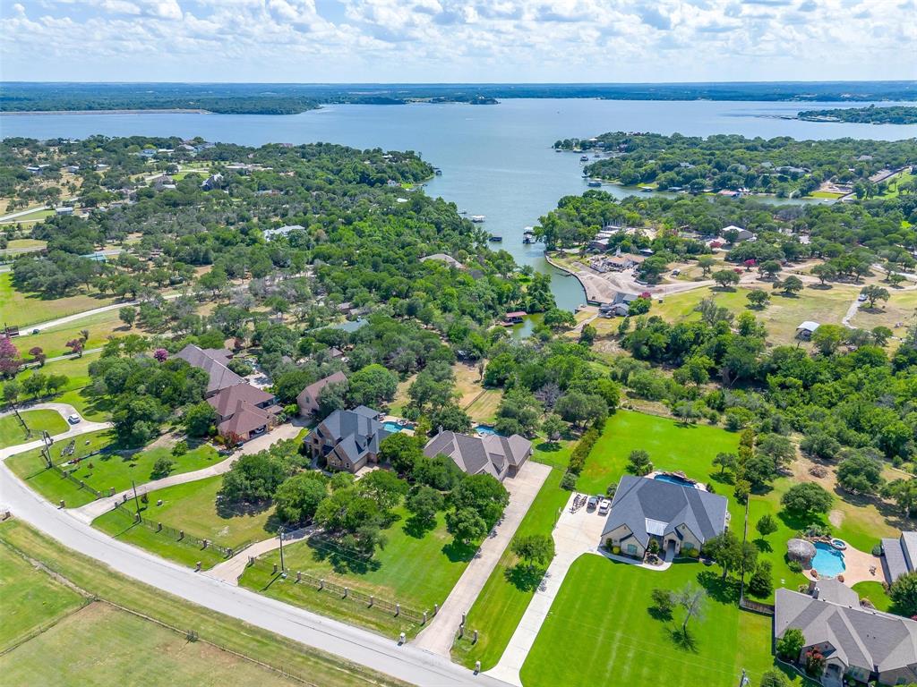 Luxurious ranch style home set upon over an acre and a half on Eagle Mountain Lake! This elegant 3-bedroom, 3.5-bathroom ranch-style residence is a masterpiece of comfort and style, designed for those who appreciate the finer things in life. Upon entering, you'll be greeted by vaulted ceilings that elevate the spacious living areas adorned with exquisite travertine and wood flooring, and built in cabinets throughout. The gourmet island kitchen, with its granite countertops and gorgeous wood cabinets, is a chef's delight. The office equipped with built-in cabinets is ideal for working from home. For those who revel in entertainment, this home is your haven. A game room with wet bar and a media room ensure endless amusement. Step outside to find your private paradise: a saltwater stone pool with a spa and waterfall, enveloped by a sprawling patio. Under a charming cedar arbor, the outdoor kitchen with a commercial grill awaits your culinary creations, while the fire pit and gazebo beckon for tranquil evenings under the stars. The master suite offers a Greek-style marble sanctuary with his and hers sinks and a massive walk-in closet —a perfect retreat at day's end. Approximately 25 ft of water frontage with lake access!