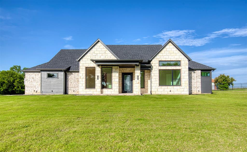 This stunning custom-built home presents a striking blend of modern elegance and timeless Texas charm. The contemporary black iron front door with glass insets creates a sophisticated entrance that hints at the high-end finishes found inside. The elegant dining room offers the perfect setting for both intimate dinners and festive gatherings. A coffered ceiling adds architectural drama and depth. Vaulted ceilings with exposed wood beams in the living area add character and a sense of grandeur. The kitchen is a showpiece of thoughtful design and timeless elegance, offering both beauty and functionality for the modern homeowner. Anchored by a massive waterfall-edge island, the space provides ample room for meal prep, casual dining, and entertaining. Double Ovens, glass cabinets, pendant lighting and an undermount sink with a beautiful backyard view are just a few highlights in this kitchen. The primary ensuite bath offers a large shower space and separate soaking tub along with separate vanities. The primary closet has two sets of built ins and 3 levels for hanging clothing. The laundry room offers additional storage with multiple cabinets. Come see this home today and all that it has to offer!

Step into a spa-like retreat in this luxurious primary bathroom. Anchoring the space is a stunning freestanding soaking tub set against a backdrop of richly textured porcelain tile and a frameless glass-enclosed walk-in shower. The shower features dramatic herringbone accent tile and dual showerheads, adding both visual impact and daily convenience.
Features in this home include beautiful hardwood flooring, spray foam insulation and piers under the foundation and a spacious 3 car garage.