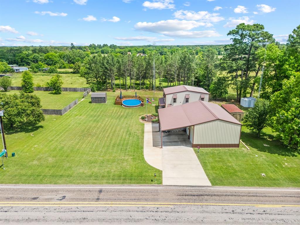 Big Bold Beautiful Barndo. Experience peaceful country living on an unrestricted .563-acre lot with 2,472 sq ft, 4 beds, 2 baths & double living areas. The drive-up appeal is exceptional featuring covered & uncovered parking, inviting porches & low-maintenance landscaping that frames the home perfectly. Step inside to a warm & rich floorplan where the living, dining & kitchen areas connect seamlessly. Hickory cabinetry, plantation shutters, upgraded trim package & lighting, porcelain tile flooring throughout the downstairs main areas, oil-rubbed bronze fixtures, and a cohesive neutral color palette create a polished feel. Chef’s kitchen features an oversized island with breakfast bar seating, SS appliances & leathered granite countertops with coordinating backsplash. Downstairs 2 spacious beds share a Jack & Jill bath complete with double sinks, abundant cabinetry, built-in linen closet & an ADA-compliant walk-in shower with porcelain tile, dual shower heads, soap boxes, bench seating & a rain-glass door. Upstairs offers maximum privacy with the primary suite, an expansive bath featuring separate sinks & vanities, another porcelain-tile walk-in shower with upgraded fixtures & an oversized walk-in closet with custom built-ins. A media room provides the perfect spot for movie nights with room to add a home gym. The 4th bedroom can easily serve as a dedicated office. The exterior is an outdoor lover’s dream. Enjoy covered patios, plus a 1,500 sqft shop with a 16x30 loft, dedicated laundry area, water, electric & a 9,000-lb two-post lift. Park all your toys with ease on the expansive concrete driveway, including dedicated RV parking. Summer fun awaits with a 22-ft above-ground pool surrounded by a stained & sealed deck. A short drive to Lake Fork, Holbrook & Tawakoni. Commuting & exploring East Texas is effortless with quick access to Hwy 69, 80, and I-20, giving you a straight shot to all the comforts, amenities, and outdoor adventures the region is known for.