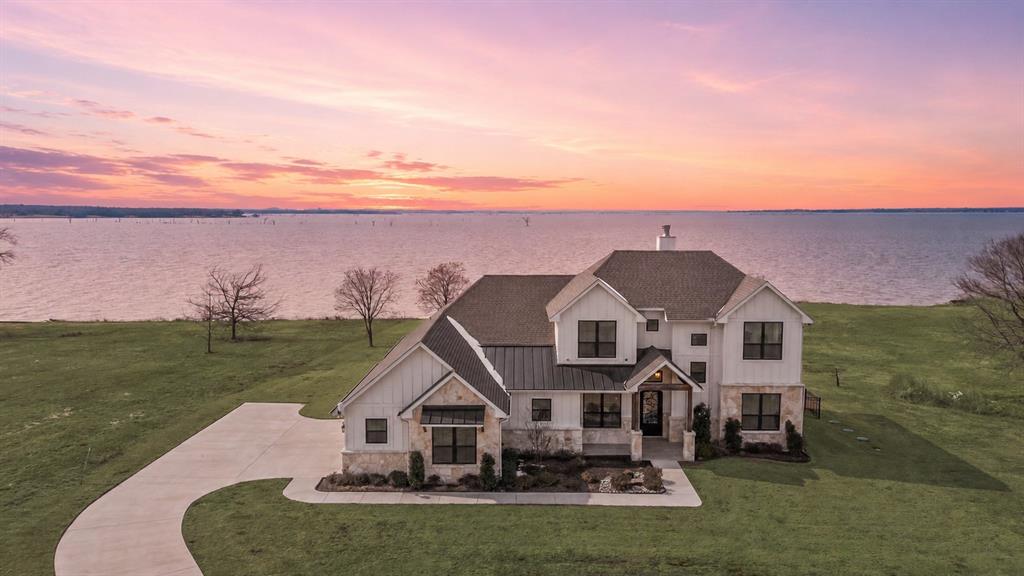 Perfectly positioned on the shores of Richland Chambers Lake, this inviting waterfront home is designed for easy lake living and peaceful water views. Tucked away on a quiet peninsula, the property offers 119 ft of shoreline with a steel retaining wall and water steps already in place—ideal for relaxing by the water and ready for a future boathouse. The exterior showcases a fresh modern farmhouse aesthetic, complemented by a 3-car garage offering ample space for vehicles, lake toys, and everyday lake essentials.

Inside, 3,402 sq ft of thoughtfully designed living space includes four bedrooms and four bathrooms. Hardwood floors extend through the main living areas, while the open layout is filled with natural light. The kitchen blends style and function with white shaker cabinetry, quartz countertops, farmhouse sink, subway tile backsplash, and a large island ideal for casual meals or entertaining. It flows into the dining area, where expansive windows and a statement chandelier set the stage for everyday dining or special occasions.

The living room is a focal point, featuring a stone fireplace and walls of windows framing tranquil lake views. Step outside to the patio and attached sunroom—perfect for morning coffee, evening relaxation, or year-round enjoyment. Upstairs, two generous family or game rooms provide flexible space for movie nights, hobbies, or guest accommodations. A discreet storage area beneath the staircase keeps the home organized. Both refrigerators, plus the washer and dryer, are included so you can move in and enjoy lake life immediately.

For added convenience, the home includes a lake pump and whole-home water filtration system. A fenced dog yard with sleek black metal fencing provides a secure, unobtrusive space for pets while complementing the modern farmhouse design.

With high-end finishes, flexible living space, and a prime waterfront setting, this home is ideal for full-time living or a weekend retreat on Richland Chambers Lake.