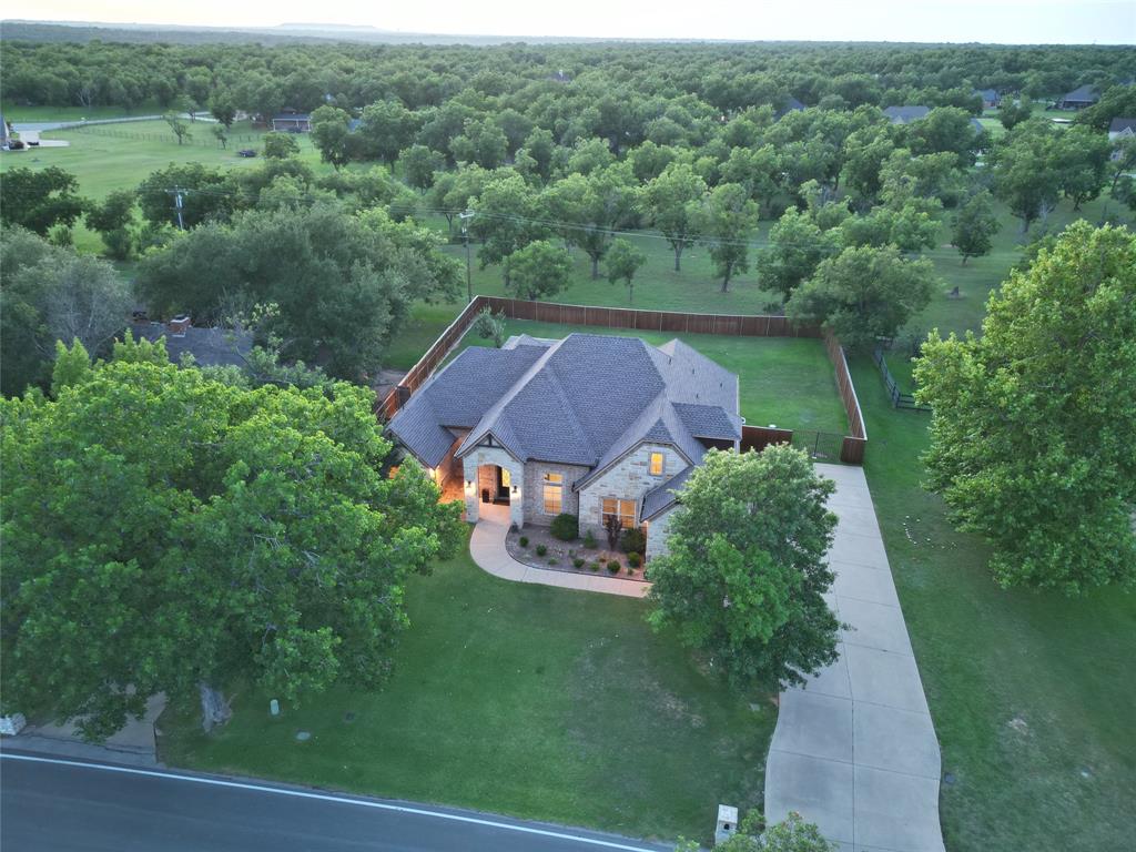 Beautifully updated 4-bedroom, 3-bath home in the highly sought-after Pecan Plantation community. This well-maintained property offers exceptional curb appeal, a spacious floor plan, and numerous recent upgrades. The updated kitchen features a large center island, propane gas cooktop, tankless water heater, and abundant workspace for entertaining. Ceramic wood-look tile flooring flows throughout the main living areas, while the primary suite boasts a fully renovated spa-inspired bathroom completed in 2025. Upstairs, the oversized bedroom with a private full bath provides flexible space for a guest suite, game room, media room, or second living area. Enjoy outdoor living on the expansive covered patio overlooking a large, private, fully fenced backyard. The oversized garage includes an additional golf cart bay, perfect for the Pecan Plantation lifestyle. Additional improvements include a propane system, oversized gutters, and a new 30-year impact-resistant roof, offering both style and peace of mind.