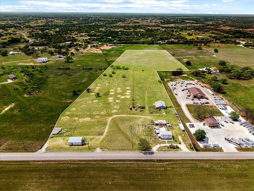 18.46 Acres outside of Weatherford city limits.COMMERCIAL POTENTIAL. UNRESTRICTED . TXDOT REPORTS 3,794+ VEHICLES TRAVEL THIS ROAD DAILY. This property is currently a super cute small cattle ranch. The home is cozy and has a cowboy flair
on the walls and floors. There are french doors leading from the living area to the large covered porch that is perfect for your family and friends BBQ's. The kitchen has a long breakfast bar and enough size for a table that can seat 12. The master is cowboyed up with a brick wall with a fireplace for extra cozy nights. There is ample parking for your vehicles, trailers and recreational vehicles as well as RV parking and hookups. You can make it your new home or live in it while you build a larger home or perhaps the emphasis would be to change the use of the land to use for industrial or commercial purposes. What ever you choose it is an ideal location. The property next door is a 5 acre Horse Trailer Lot and the property that just sold on the other side of it is set up to be small Industrial park. The property is flat and fenced and cross fenced and has a barn and a 24x42 workshop with 220 electric
and water.