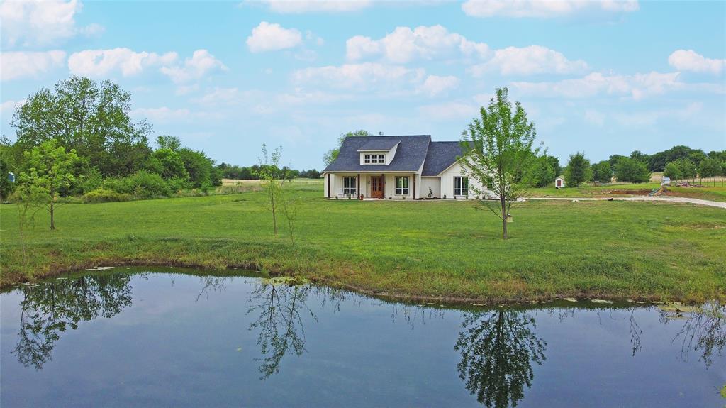 Beautiful, easy country living with low taxes and thoughtful custom design touches throughout are the hallmarks of this family-focused home. Sitting far back from the road for privacy, you’ll drive home past mature pecan trees and your own pond every day. Walking across the welcoming front porch, you will immediately notice the wide-open spaces and light from the oversized windows. 8 ft interior doors, a hewn beam accent in the living space, and a terrific kitchen layout with a huge pantry and premium finishes are exactly what you’d hope for in a modern farmhouse design on 2.5 acres. The oversized primary suite features a vaulted ceiling, a spa-like bath and connects directly to the laundry room for everyday convenience. Enjoy massive, covered porches overlooking wide open land, plus chicken coops ready for your homestead setup. Easy access to Hwy 69 or Hwy 34 keeps commuting simple while still offering peaceful rural living. An AV cabinet next to the fireplace will be installed before the home becomes yours, adding even more functionality. Don’t miss the oversized garage, the firepit or the house-matching chicken coop!