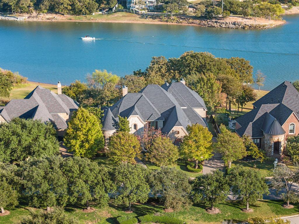 Stunning LAKEFRONT ESTATE on Lewisville Lake, perfectly positioned on a private cul-de-sac with breathtaking views and direct deep-water access. This custom estate sits on an expansive lot behind a private security gate and was designed for both luxurious living and unforgettable entertaining. Step inside to find vaulted ceilings, rich hardwood floors, and an open layout showcasing the chef’s kitchen with high-end appliances, multiple dishwashers, a spacious butler’s pantry, and a temperature-controlled wine room. The primary suite offers a spa-inspired bath with a walk-in steam shower for the ultimate retreat. Enjoy multiple living and flex spaces, including a dedicated exercise room or nursery, an upstairs game and card room with balcony, upstairs utility closet and a 1,000 sq ft bonus area ready to build-out your golf simulator or extra living quarters. The home has four HVAC units ensure comfort throughout every season. The true showpiece is the outdoor oasis: an oversized pool and private spa, cabana with fireplace, full outdoor kitchen with ice machine, an outdoor shower and access to a pool bathroom. Automatic electric screens wrap around the patio, extending your living space year-round. A 3-car oversized epoxy-floored garage completes the property. Residents enjoy excellent community amenities including a pool and green-spaces. With private lake access, deep water, and unmatched views, this home is truly a MUST-SEE LAKEFRONT SANCTUARY where no detail has been spared.