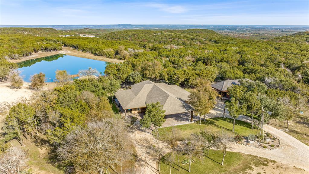 Beautiful custom home with private lake on 20 secluded acres that could also be repurposed as a short-term vacation rental or a special events venue. Property has dense tree cover that provides excellent wildlife habitat and is bordered on 2 sides by large, undeveloped ranches. The 1-acre lake has 20 ft depth and is stocked with multiple species of bait fish, plus crappie, black bass, and channel cat. All 4 sides of the property are cleared at the boundaries, and perimeter fencing exists on 3 sides. The 2,166 sqft home has an impressive 30x35 covered parking area at the entrance, as well as covered porches with lighting on the remaining 3 sides, all of which feature stamped, stained concrete. These porches create a dramatic outdoor living space with views of the beautifully landscaped yard with St. Augustine grass and walkway to the lake.

The home's entryway leads into a spacious living area with vaulted wood ceilings with exposed beams and a stacked-stone WB fireplace with insert. The open concept design also features a roomy kitchen and dining space with large windows overlooking the backyard and lake. The kitchen has granite countertops, propane oven-stove, and stainless appliances. It also has a large island with electricity, a granite prep space, and a custom cedar countertop on the dining space. The primary bedroom and bath have exposed wooden beams, wood floors, his-her walk-in closets, separate vanities with cedar countertops, and a large, tile shower. The home also incorporates energy efficient features such as Low-E windows and open cell foam insulation. Outbuildings include storage space with a roll-up door and room for parking, and it also houses the well water storage tank.

The location is convenient to both Glen Rose and Stephenville, as well as the Metroplex and Waco. Road frontage includes 800+ ft of paved County Road 2012 frontage. Glen Rose ISD.