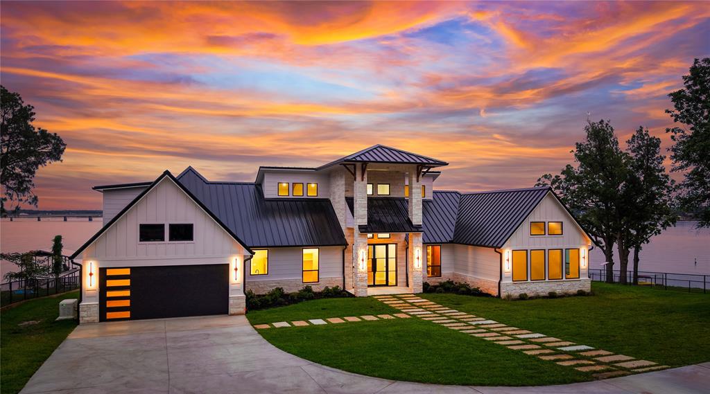 Estate-style waterfront new construction on approximately .58 acres with 230’ of shoreline, new boathouse, expansive outdoor living, 4-bay climate controlled shop with guest quarters designed to fully embrace luxury lake living and entertaining. The 4,682 sq ft main residence offers 7 bedrooms, office, and 6.5 baths including two waterside primary suites, expansive windows, grand iron glass front door entry, soaring wood-beamed ceilings, and stone wood-burning fireplace. The chef’s kitchen features a 10’ island overlooking the living area, Wolf appliance package with 8-burner double oven range, built-in refrigerator, microwave, dual pantries, decorative lighting, and wood flooring throughout. Oversized utility room includes sink, refrigerator space, and abundant cabinetry. Designed for entertaining and large gatherings, the floor plan includes two waterside primary suites, three additional downstairs ensuite bedrooms, private office-study, and an upstairs bunk room with four full-size bunks, full bath, and add'tl bedroom. Outdoor living is enhanced by a covered lakeside kitchen and patio with stone wood-burning fireplace, built-in gas grill, separate griddle, refrigerator, and ice maker. New boathouse with composite decking, two boat slips including upgraded lift and cradle designed for a larger wake boat with GEM remotes, dual PWC lifts, covered seating area, entertaining party deck, and expansive upper deck storage. A beautifully landscaped circle drive and electric gated entry lead to the 4-bay spray foam insulated shop with epoxy floors, and mini split HVAC systems, plus detached 620 sq ft 1 bed, 1 bath guest quarters featuring a full kitchen, living area, dedicated bedroom with walk-in closet, stackable washer-dryer, wood floors, and water views. Generac whole-home generator, well water with 1,550-gallon fresh water tank, and buried propane tank complete the property. Near The Dock resturant and Historic Downtown Malakoff with coffee shops, boutiques, and more.
