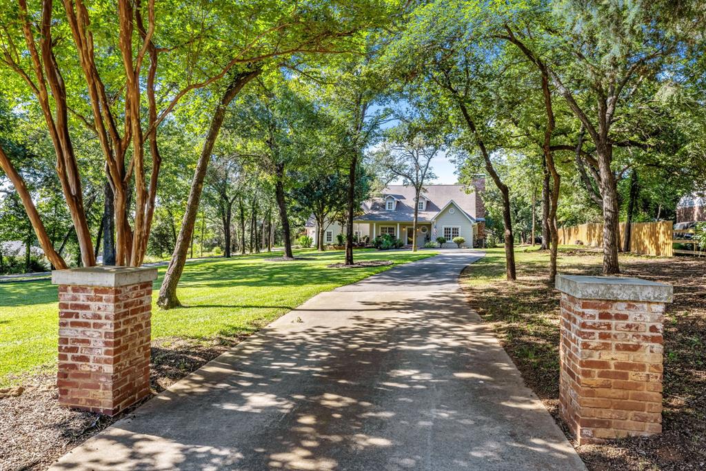 Discover an extraordinary lakeside retreat nestled in one of Oak Point's most desirable communities, just 10 miles from the Dallas North Tollway. Set among towering mature trees on a beautiful private homesite, this exceptional residence offers a rare combination of luxury, tranquility, and direct access to the natural beauty of Lake Lewisville.

A meandering path winds through the property, leading to a secluded lake cove and providing direct access to the water for endless outdoor enjoyment. Inside, the thoughtfully designed floor plan showcases 5 spacious bedrooms, including 2 bedrooms on the main level, 4.5 baths, and 3 expansive living areas that offer remarkable flexibility for both everyday living and large-scale entertaining. Walls of windows frame sweeping views of the heavily treed setting, creating a seamless connection to nature throughout the home.

The updated chef-inspired kitchen is designed to impress, featuring generous workspace, abundant storage, and premium amenities sure to delight culinary enthusiasts. A welcoming covered front porch invites relaxation, while the long circular driveway and 3-car garage provide ample parking for family and guests.

Additional highlights include wiring ready for a generator, ensuring peace of mind during power outages, and a private water well for unrestricted irrigation of landscaping and vegetation—an exceptional benefit that helps maintain the property's lush surroundings at no additional watering cost. Four fireplaces throughout the home create a cozy atmosphere during crisp fall days and long winter evenings at home!

Offering privacy, convenience, and an unparalleled quality of life, this remarkable Oak Point residence presents a rare opportunity to enjoy lake living just minutes from the conveniences of North Dallas.