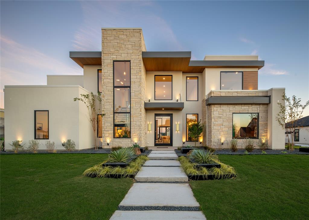 Discover a striking modern masterpiece where bold architecture meets refined comfort. Soaring 20-ft ceilings, a dramatic floating staircase, and expansive walls of glass fill the interiors with natural light while framing serene views of the heated pool and spa. Perfectly positioned on a spacious half-acre lot in the prestigious Ridge Lakes community, this home is designed for effortless indoor-outdoor living and entertaining. The resort-style backyard serves as an inviting retreat, featuring a covered lounge with sitting and dining areas, a fully equipped outdoor kitchen, and a sleek pool deck ideal for gatherings both large and small. Inside, the chef’s kitchen impresses with imported cabinetry, German hardware, Taj Mahal quartzite countertops, and premium appliances. Additional highlights include custom designer lighting, white oak flooring, foam insulation, app-controlled exterior lighting, and a four-car garage. The main level hosts the primary suite, guest suite, and private office, while the upstairs offers three generous bedrooms and a media room with its own powder bath. Zoned to top-rated Rockwall-Heath schools, this design-forward home delivers the ultimate in modern luxury and everyday comfort in one of Heath’s most sought-after communities.