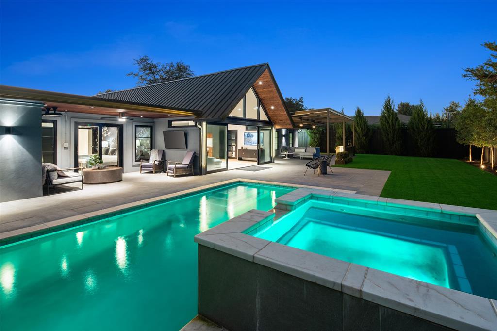A striking blend of contemporary architecture and California-inspired design, this fully reimagined luxury residence showcases high-end craftsmanship, seamless indoor-outdoor living, and resort-style amenities throughout. A dramatic gallery-style entry opens to an expansive great room with soaring ceilings, wide-plank white oak floors, and oversized windows that flood the home with natural light. Designed for both everyday living and elevated entertaining, the open-concept layout centers around a sculptural waterfall-edge marble island in the chef’s kitchen, complete with a full Thermador appliance suite including a gas cooktop, double ovens, dual sinks, and dual dishwashers. Sleek custom Florense cabinetry from Brazil adds modern sophistication, premium storage, and designer finishes throughout the kitchen and primary suite. Floor-to-ceiling designer tile elevates each bathroom with a spa-inspired aesthetic and bespoke modern detailing. The luxurious primary retreat features dual custom closets with Florense built-ins, creating a refined balance of beauty and functionality. Three oversized sliding glass doors provide seamless access to two covered patios, a fully equipped outdoor kitchen, and a private backyard oasis with a sparkling resort-style pool, ideal for entertaining and year-round indoor-outdoor living. Thoughtfully curated with premium materials, expansive entertaining spaces, luxury finishes, and warm modern design, this exceptional residence offers the perfect combination of architectural sophistication, comfort, and California-style luxury living.