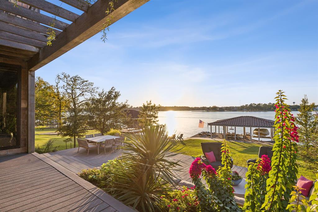 INCREDIBLE SUNSET! A rare opportunity to experience luxury lakefront living on prestigious Hogan peninsula. This serene retreat features 4 bedrooms, 4 full baths, and 2 half baths (1 interior, 1 exterior). A private staircase and elevator provide exclusive access to the expansive primary suite showcasing panoramic lake views, electric black out and sun shades, separate his and hers baths and closets, a jetted tub, balcony, stately wood-paneled office, studio and home gym. The open-concept kitchen, dining and living rooms feature floor to ceiling sliding glass doors and windows that frame spectacular views. Gourmet kitchen features a Wolf 48” dual-fuel range, 36” SubZero refrigerator and freezers, Perlick crushed ice maker, granite countertops and custom Bentwood cabinetry. Fresh paint throughout, completed in January 2025, enhances every room with a crisp and timeless finish. Remodeled in 2018 with focus on entertaining, guests will enjoy effortless flow to 1,100 sf tiered terrace, pergola, outdoor dining space, sunset and stargazing deck, all overlooking unparalleled lake views. The boat dock is equipped with dining space, a shower, double jet ski and boat lifts and a cozy fire-pit. Although the small original foundation of this house was built in 1971, two major renovations were completed in 2007 and 2009. The addition of the living room, dining room, kitchen, upstairs primary suite, office, workout room, laundry room and garage were built on newer pier and beam foundation as late as 2009, while the porte cochere and living suite above were built in 2007. New electrical, plumbing and septic were added with these updates, as well as the addition of the fireplace, interior work shop, and the concrete tile roof.