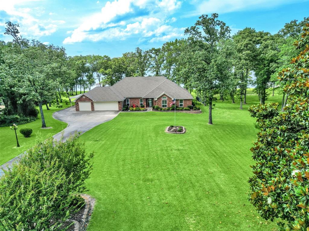 Waterfront dreams begin on legendary Lake Fork home of world-class bass fishing. This beautifully updated single-story retreat sits on a rare double lot with over 1.46 acres, not including SRA leaseback. Enjoy room to roam along 400+ feet of shoreline with unobstructed open water view and main lake access. Park-like grounds, towering trees, and breathtaking lake views from nearly every room. Inside, the wall of windows frames the water while the Texas-sized great room invites gatherings and lifelong memories. The remodeled kitchen shines with quartz counters, stainless steel appliances, gas range, generous prep space, and breakfast room for quiet mornings. A serene primary suite offers tranquil views, dual closets, and a spa-inspired double marble shower. Two additional spacious guest rooms with updated baths allows a quiet space for guests. A private office with built-ins and closet offers a flex space or 4th bedroom. Enjoy the dining room for dinners or game night. Updated laundry room with sink, second refrigerator and plenty of built-ins complete the interior. Step outside and life slows down. Sip coffee under the covered patio as birds greet the morning, spend afternoons on the large deck beneath the Texas sky, and watch deer wander by at dusk. Follow the private walkway to your own covered boathouse with double slips, pier, and front-row seats to unforgettable sunsets. The oversized 3-car garage + carport includes EV charger and is ready for all your toys. Brand new HVAC system and duct work May 2026, RO system, new windows, designer + LED lighting, new hardware and all new electrical receptacles complete the updates. Natural gas. Neighborhood boat ramp makes experiencing lake living at its finest easy. Zoysia grass.
