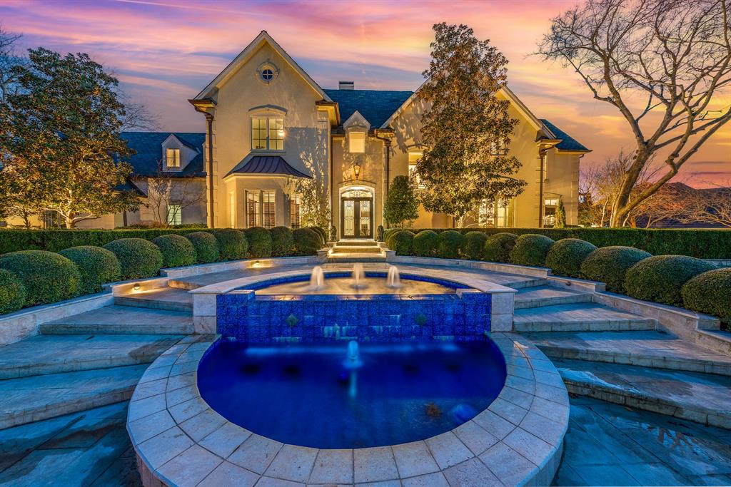 Under Contract with same buyer twice, past inspection and option period, fell out due to personal reasons with buyer! Tucked behind the gates of one of Heath’s most coveted luxury communities with stunning views of Lake Ray Hubbard, 121 Blue Heron Lane feels less like a home and more like a private retreat. Surrounded by nearly an acre of lush greenbelt and serene water views, this French Château inspired estate offers a level of privacy and tranquility rarely found so close to Dallas, just 25 minutes away.
The first impression is striking. Manicured grounds, an elegant fountain, and timeless architecture create a setting at once grand and intimate. Inside, the home unfolds with warmth and sophistication, where natural light pours through expansive windows, framing peaceful views and creating a seamless connection to the outdoors.
Life here is centered around experience. Mornings begin with coffee overlooking the water and the quiet beauty of the 10 acre pond and protected wildbird nature preserve just beyond your backyard. Afternoons invite peaceful walks through the surrounding greenspace, and evenings are designed for gathering, whether hosting elevated dinners or simply unwinding in your own private escape. The setting offers a rare connection to nature while maintaining a sense of refined exclusivity.
The outdoor living is where this estate truly shines. Designed for both relaxation and entertaining, the backyard delivers a true resort style experience with a heated pool and spa, fire and water features, an outdoor kitchen, and multiple spaces to lounge and dine while taking in the natural surroundings. It is the kind of setting that makes everyday living feel like a getaway.
Inside, the thoughtful layout offers both privacy and flexibility, with multiple living spaces, luxurious bedroom retreats, and accommodations ideal for guests or multigenerational living. Every detail supports a lifestyle that feels elevated yet effortless.