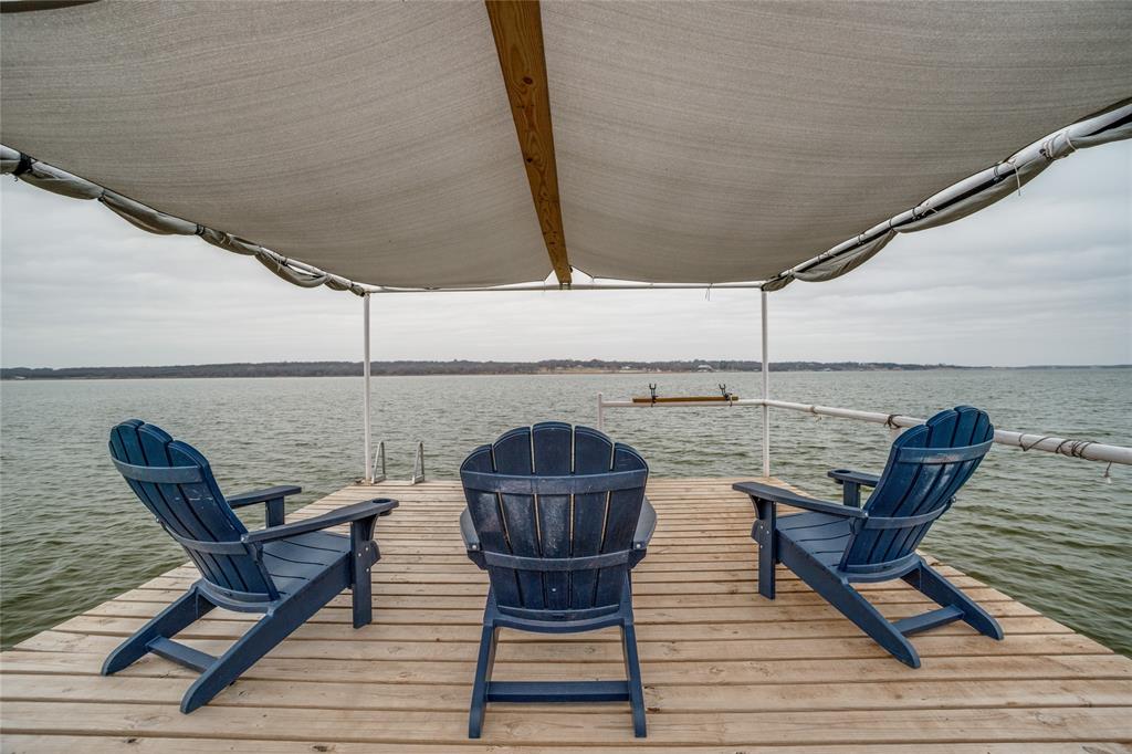 Fully updated lake front property on beautiful Lake Nocona w guest home & so much more! Property has rental potential w guest house w separate entrance. Lease out both sides for a dual-income property! So many possibilities! Main home has 2 bedrooms, 2 bathrooms with large screened in front porch & breathtaking lake views! Wonderful open floorplan makes this home ideal for gatherings big & small. Spacious living room w wood-burning fireplace opens to kitchen & dining area. Kitchen features honed granite countertops, stainless steel appliances, breakfast bar & custom cabinetry. The private Primary suite features ensuite bath & direct access to hot tub on back deck. Secondary bedroom & bath are just across the hall. Main home has been fully updated with luxury vinyl plank throughout, new appliances, windows, water heater & the list goes on! The guest home is attached by the spacious carport & has 1 bedroom, 1 bathroom, a full kitchen & spacious living area. Outside, you’ll find everything you dream of in a lake house! New oversized covered deck with hot tub, custom railings and plenty of room for everyone to relax and take in those lake views! New covered cooking space is every grill master’s dream! New 12’ x 24’ metal shop, 2 additional storage buildings and an ample amount of parking area for both houses as well as boat parking space. There are so many memories to be made here with family and friends, including an AMAZING fireworks show on the 4th of July-right from your own updated boat dock with new decking & soft cover. Property sits on just over half an acre, so there is plenty of room for everyone! All of this is within the gated community of Nocona Hills that has 24-hour manned security gate, 18-hole golf course, additional 50-acre fishing pond, grass landing strip, RV park w picnic area & more! THE BRAND NEW NOCONA HILLS COUNTRY CLUB IS SCHEDULED TO OPEN IN 2026, INCLUDING ON-SITE RESTAURANT & BAR, PRO SHOP, BALLROOM, SWIMMING POOL & PICKLE BALL COURT.