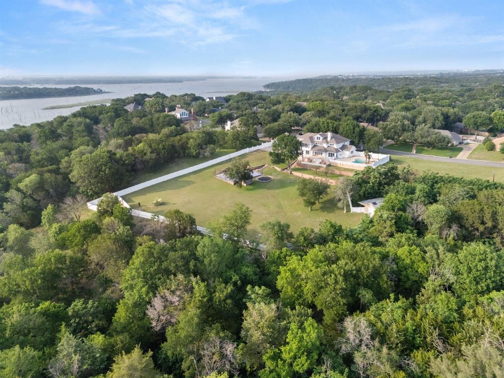 Rare 7,000 sqft home on over 5 acres in Woodway, TX. This is where luxury meets outdoor adventure.
Tucked behind the mouth of the Bosque River in one of Woodway's most coveted addresses, this extraordinary estate makes you feel like you've arrived and escaped all at once. Giant front doors open into a sunlit living room with soaring ceilings and oversized windows framing sweeping nature views. An elevator anchored like architectural art signals immediately that this home was built without compromise. Set on 5.49 acres, this 7,270 SF masterpiece was built for those who refuse to choose between refined living and wide open adventure. Every room floods with light and those legendary Woodway sunsets. The downstairs primary suite features one of six fully renovated bathrooms, each finished to turn a daily routine into a daily indulgence. Upstairs, three additional bedrooms and bonus spaces offer room to grow. A secondary primary suite on the opposite wing gives guests their own world entirely. A resort style backyard features a sparkling pool and sports court backed by your own private slice of nature. A massive shop sits tucked into the treetops, ready for big projects or every tool and toy the property demands. The den anchors the home with a wet bar and pool table. Nobody leaves early. The office conceals a hidden room behind one of the shelves, adding a sense of wonder that fits the adventure of this property. The chefs kitchen delivers with full sized built in refrigerator and freezer. Ascend by staircase or elevator to a purpose built third floor movie room, plus a screened in porch perfect for a plant room or quiet retreat. The new owner can subdivide and build additional homes, making this a rare investment play in one of Woodway's most desirable pockets. Zoned to Midway ISD. This is a lifestyle, a legacy, and a once in a generation opportunity on the Bosque.