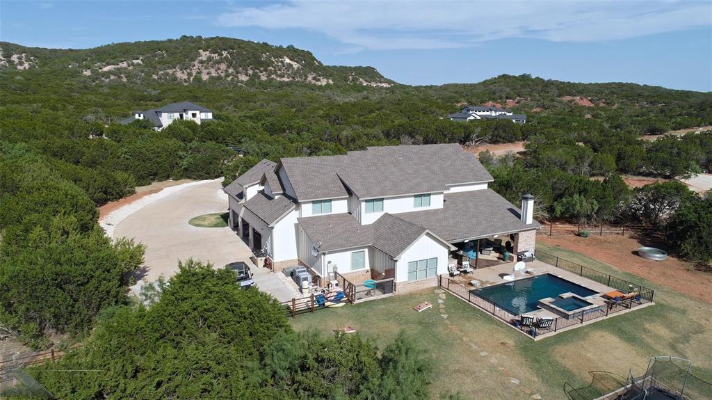 Little slice of Texas heaven nestled into well established gated South Fork Subdivision on 20.41 acres of your own!  Custom built  home has immeasurable details from top to bottom built by Kyle Paul Construction.  This beautiful home maximizes all square footage with 7 bedrooms, 5 full bathrooms, large open living-dining-kitchen space with high ceilings, 3 car oversized garage, and large landscaped yard.  Two of the upstairs bedrooms could be converted to a media room if desired.  There is a large pantry with a coffee bar, sink and microwave.  The utility room features hook ups for 2 full size washers and dryers with a sink and folding area.   Beat the summer heat in the large pool with hot tub.  The back patio has a wood burning fireplace, large sitting area and outdoor kitchen.  3,657 sq ft  barn with feed room, tack room, half bathroom and three stalls.  The barn has a 4 car garage-shop area and a 558 sq ft unfinished loft area.  Custom built lighted bridge connects the 2 properties