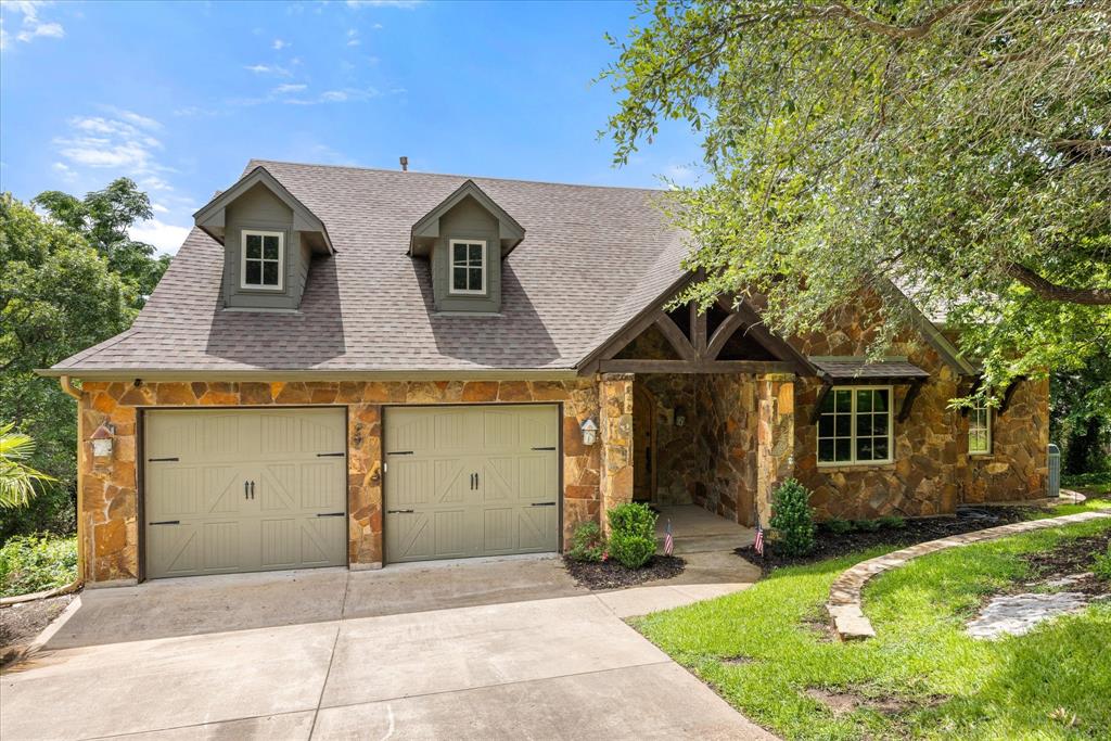 Tucked among mature trees and just five minutes from Highway 377, this stunning three-story lake house delivers the rare combination of privacy and easy access. With five bedrooms, five full baths, and one half bath, the home is designed to host family and friends in true lake-life style — all wrapped in warm, log-cabin character that feels like a permanent retreat. Step through the front door on the second story and you're greeted by an expansive living room anchored by floor-to-ceiling windows that flood the space with natural light and frame breathtaking views of the water. The open-concept kitchen and living area is built for gathering — whether it's morning coffee with the sunrise or a full house after a day on the lake. The chef's kitchen is outfitted with premium Thermador appliances, including a high-end cooktop, oven, refrigerator, and dishwasher, combining luxury, performance, and timeless style.  Head upstairs to a one-of-a-kind loft bedroom featuring six built-in bunk beds — the kind of space that makes every weekend feel like camp, and every guest feel like they've got the best room in the house. Downstairs, the first story opens into a second family room, plus two additional bedrooms and full baths, giving everyone room to spread out. Outside, the property keeps delivering. Multiple balconies provide elevated vantage points over the surrounding trees and lake, while the waterfront is built for making memories. Enjoy the convenience of two private boat docks, including a spacious main dock with a swimming platform that's perfect for swimming, fishing, relaxing, or launching your next day on the water. The natural surroundings create a secluded feel that's hard to find this close to town, yet you're only five minutes from Highway 377. Located in Granbury ISD, this exceptional waterfront retreat checks every box — space, luxury, privacy, and unmatched lakefront amenities, all wrapped in the timeless charm of a true log cabin.