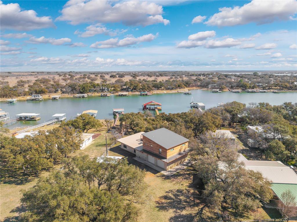 $50,000 price drop! Set on a prime stretch of Lake Brownwood is this beautifully rebuilt waterfront retreat offering the perfect balance of craftsmanship, comfort, & laid-back lake living. Ideal as a weekend escape, family retreat or a full-time residence this property delivers privacy, space, & timeless appeal.

Originally built in the early 1960s, the home was taken to the studs & fully rebuilt in 2018, including new plumbing, electrical, foam insulation, an oversized garage, & a second-story addition. The result is approximately 2,415 square feet with 4 bedrooms (2 up, 2 down) & 2 & half baths. Large windows on both levels flood the home with natural light & showcase serene lake & treetop views.

The kitchen & baths feature granite countertops & custom alder cabinetry, while a stained pine ceiling adds warmth to the kitchen & family room. The exterior makes a statement with Leuders limestone on the first floor & Ipe wood siding above—an exceptionally durable, decay- and fire-resistant hardwood. A 20' x 17' Ipe rooftop deck creates an elevated outdoor living space perfect for entertaining or sunset views.

Modern functionality is built in, including an oversized two-car garage with 240-volt EV or RV hookups, separate HVAC systems, two water heaters, LED lighting, a cell phone booster, satellite TV wiring, & all major appliances included. A 20' x 16' metal storage shed adds convenience, & the BBQ patio & pump house roofs were replaced in 2025.

The standout feature is the oversized boat dock, built in 2017 with heavy-duty construction. Measuring approximately 49' x 31', it sits in 14 to 16 feet of water when full & offers composite decking, LED lighting, a covered upper deck, two boat slips with lifts, a dual WaveRunner bay, built-in storage, a retractable swim ladder, & a 3 light fishing system.

More than a lake house, the home is a refined waterfront lifestyle—designed for comfort & positioned in one of Lake Brownwood’s most desirable settings.