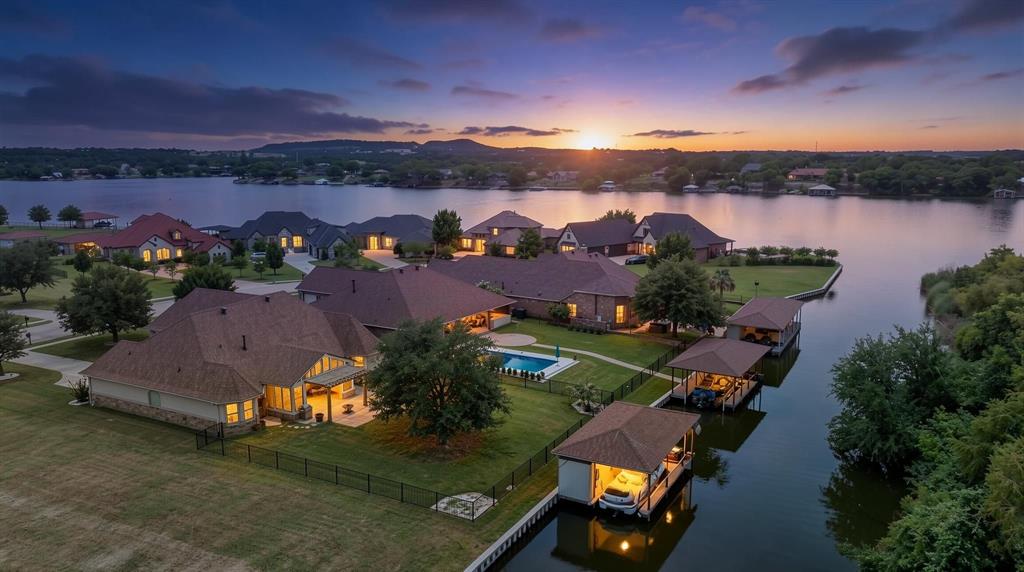 Exceptional waterfront living in The Island, Granbury's premier gated lakefront community. Built by renowned local builder Couto Homes, this luxury waterfront property is being sold fully furnished and includes a Hurricane Sundeck boat, Yamaha jet ski, and Dolphin trolling boat, creating a true turnkey lake lifestyle.

Situated on a large waterfront lot the home is just seconds from the main body of Lake Granbury. The private dock features separate lifts for both the boat and jet ski. The fenced backyard offers plenty of room for a future pool and is irrigated directly from lake water.

Inside, quality craftsmanship is evident throughout with elaborate molding, designer chandeliers, premium light fixtures, plantation shutters, automatic window shades on picture windows, and solar shades on the sunny side of the home. The spacious living room features a dramatic floor-to-ceiling stone fireplace and overlooks the water. Surround sound enhances both everyday living and entertaining.

The gourmet kitchen is equipped with an induction cooktop and is also plumbed for gas. The desirable split-bedroom floor plan includes 3 bedrooms, 2.5 bathrooms, a dedicated office, and a second living area complete with a pool table.The primary suite offers a private retreat, while guest bedrooms are thoughtfully separated from the main living areas. Easy modifications could make the office into a fourth bedroom with ensuite bath.

Outdoor living is equally impressive with a screened patio featuring ceiling fans, a misting system, and an electric retractable shade. Beyond the screened porch is an extended patio with pergola cover, creating multiple spaces to relax and entertain.

Recent updates include a new HVAC system and a new Class 4 impact-resistant shingle roof. 

Opportunities to purchase a fully furnished waterfront home with boats, personal watercraft, private dock, and premium upgrades in The Island are rare. Move in and start enjoying lake life immediately.