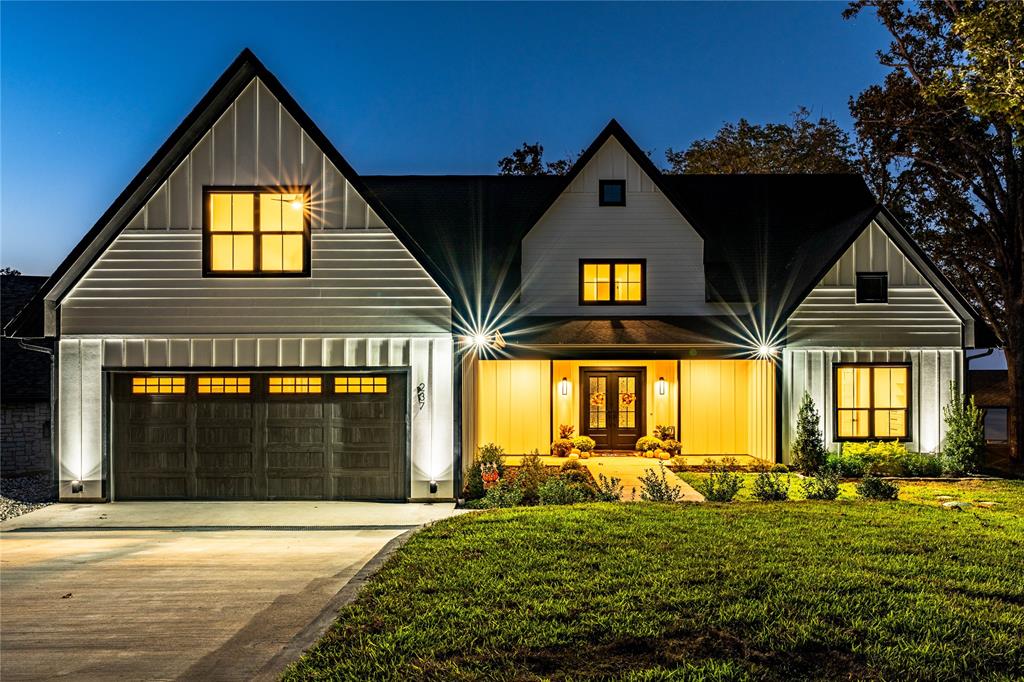 Stunning New Construction! Nestled in an exclusive and private neighborhood, this breathtaking 5 bedroom, 4 bath home offers everything you could want for luxury living. With a wall of windows revealing beautiful lake views, this home features two living areas and two laundry rooms for the ultimate comfort and convenience. Inside enjoy the warmth of engineered wood floors and cozy gas log fireplace. The gourmet kitchen is a chef's dream, boasting quartz countertops, two dishwashers, an ice machine and a beverage refrigerator - ideal for entertaining. Step outside to your huge covered porch, surrounded by professional landscaping and a custom fire pit. The double boathouse featuring a sun deck is perfect for soaking in the scenic surroundings.