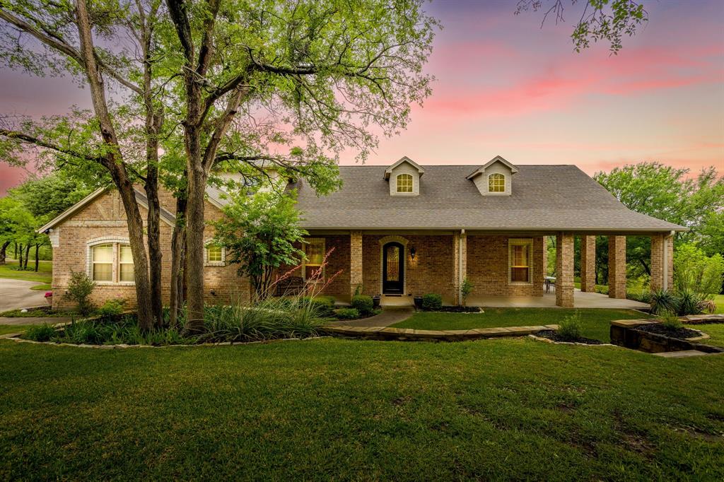 Set on a quiet, private stretch of waterfront on the Fort Worth side of Lake Granbury, this rare custom home offers the ideal balance of seclusion, accessibility, and a beautiful view of the lake. Positioned in a protected cove with a clear sightline to the main body of water, the property delivers both calm shoreline living and scenic water vistas. Built in 2012 by Couto Homes, this fully custom 4-bedroom, 3-bath home was thoughtfully designed with oversized walkways and doorways to provide ease of movement and wheelchair accessibility throughout. The open-concept floor plan is anchored by expansive floor-to-ceiling windows that frame the lake, filling the home with natural light and uninterrupted views. The main living area features a gas fireplace and flows seamlessly into the kitchen and dining spaces, creating an ideal setup for both everyday living and entertaining. The primary suite is located on the main level and includes a private exterior door leading directly to the wraparound porch, perfect for quiet mornings or evening lake views. Outdoor living is a standout feature, with a wraparound porch spanning three sides of the home (excluding the garage side), offering multiple vantage points to enjoy the water and surrounding landscape. The 1.29-acre property consists of three parcels, with the main parcel currently benefiting from an agricultural exemption.
Additional highlights include: Private well water; Lake-fed sump pump for the sprinkler system; Covered dock with space for a boat and jet skis; Extensive stone retaining walls that terrace beautifully down to the water’s edge.
Located within a small, low-impact HOA community, this property offers a rare opportunity to own a private, well-built waterfront home with both functionality and timeless design. Schedule your private showing today to experience this exceptional lakefront property in person!