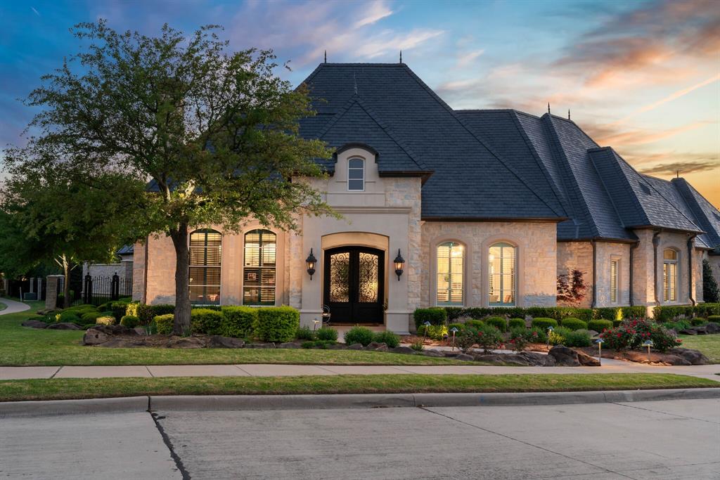 Experience timeless elegance and refined luxury in this custom John Kelley-designed French Country estate, nestled on a spacious double corner lot within the prestigious Bluffs at Chapel Creek. This remarkable one-story residence offers 6,917 square feet of meticulously crafted living space, artfully wrapped around a serene private backyard oasis. The home’s stately slate roof and authentic stone façade set a tone of sophisticated charm, while double iron doors and classic gas lanterns welcome you into a grand interior where quality and design converge. The heart of the home is the stunning main living area with a wood-beamed vaulted ceiling, seamlessly connected to two additional living spaces and a gourmet kitchen—perfect for both entertaining and everyday living. An elegant office near the entry features custom pocket doors for stylish privacy, and a gated entry leads to a porte-cochère and two generously sized garages, one of which is temperature controlled with two lifts, ideal for car enthusiasts. Outdoors, enjoy a beautifully designed patio complete with ghost screens, a stone fireplace, built-in heaters, and a misting system, offering the ultimate year-round retreat. With four spacious bedrooms and seven luxurious baths, every detail in this home caters to comfort and elevated living. Located in a community known for its lush green spaces and access to scenic hike and bike trails, this home is more than a place to live—it’s a lifestyle. Don’t miss the opportunity to experience this extraordinary estate in Frisco.