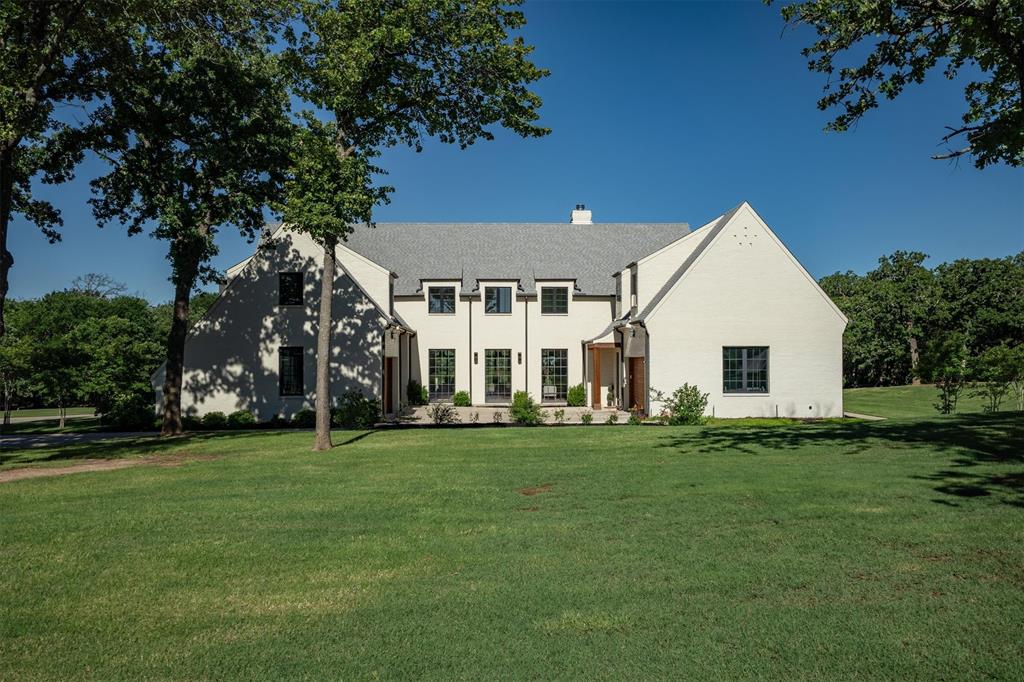 Tucked beneath a canopy of mature trees on 2.5 private, wooded acres, this striking custom modern farmhouse by renowned builder Lewis & Earley is a masterclass in style, craftsmanship, and functionality. Blending modern European elegance with the warmth of transitional design, this estate features 6 bedrooms (2 on the main level), 5.5 baths, and magazine-worthy interiors filled with curated finishes. From the white oak hardwood flooring and Black Calcutta marble countertops to the Anderson windows and custom drapery, every detail was thoughtfully selected. The heart of the home is the show-stopping kitchen—anchored by a large island, rich green cabinetry, dual dishwashers, and commercial-grade appliances—designed to entertain with ease. A jaw-dropping walk-in pantry, bookmatched marble backsplash, and designer lighting make every corner shine. The vaulted primary suite feels like a private retreat with a spa-like bath and a boutique-style custom closet. Additional highlights include 3 separate laundry areas, a water softener system, and a 4-car garage. Outdoors, enjoy a gated pool, covered patio with a Phantom retractable screen, cozy fire pit, full-yard irrigation supported by an 800 ft. well, and even a backyard zip line. Surrounded by nature and designed to impress, this home is truly one-of-a-kind—luxury living with room to roam. Located in top-rated Argyle ISD and minutes from Liberty Christian School.
