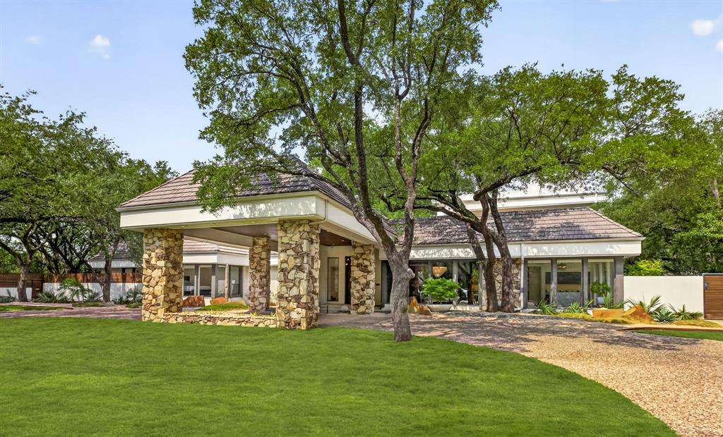 Tucked off Royal Lane in a quiet cul-de-sac, this home sits on a rare one-acre, heavily treed lot in Russwood Acres. It does not face Royal, you feel that the moment you turn in, with the canopy from all the Live Oaks. This is a 1970s modern home that still honors the architect's original vision. Stone stack walls move from outside to inside. A 20-foot porte cochère sets the scale. Heroic Sunburst front doors greet you at the threshold. A full cosmetic and systems renovation in 2020 brought everything current without erasing the soul. The powder bath stays original, because that 70s vibe is the point. The unseen star is the glass. Windows of every size bring nature, the light, and the views of the pool in. The kitchen runs on Wolf and Miele, with custom cabinets built for the way you actually cook. Downstairs holds four dedicated bedrooms, including a primary that opens to the pool. Upstairs adds a second primary suite, a great room, a balcony over looking the pool, plus a loft that works as an 2nd office or gym. The current office overlooks the pool with a full en-suite bath, so it can flexes as another bedroom whenever you need it. For visiting parents, in-laws, or a college kid back for the summer, the second floor gives them their own world. The upstairs is already plumbed for a bar when it's time. This home was built to host. A graduation party that flows from kitchen to pool to lawn without anyone bumping elbows, or the best 300 person baby shower. The three-car garage fits a lift for a fourth if you want. Lutron Caseta runs the lights. A fire suppression system is present. The crawl space is encapsulated, lit, with a sump pump and dehumidifier. There are 5 HVAC units to ensure your comfort. You are central to everything Dallas. Love Field & DFW airports and downtown are short drives. One-acre, mature trees, private, this is rare ground.