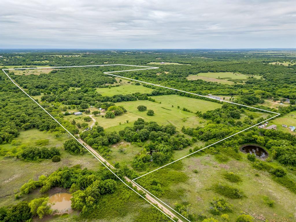 Sprawling across 86 scenic acres in Perrin, this North Texas ranch is all about space, privacy and usable land. A mix of open pastures and mature hardwoods creates ideal habitat for cattle, horses and wildlife, with gently rolling terrain, multiple ponds and established grasses enhancing both agricultural and recreational potential. The modest farmhouse offers a comfortable home base or guest quarters while you run cattle, hunt, ride or plan a future custom build. With paved road access, big skies and room to roam, this is a rare opportunity to own a classic Jack County ranch with endless possibilities.
