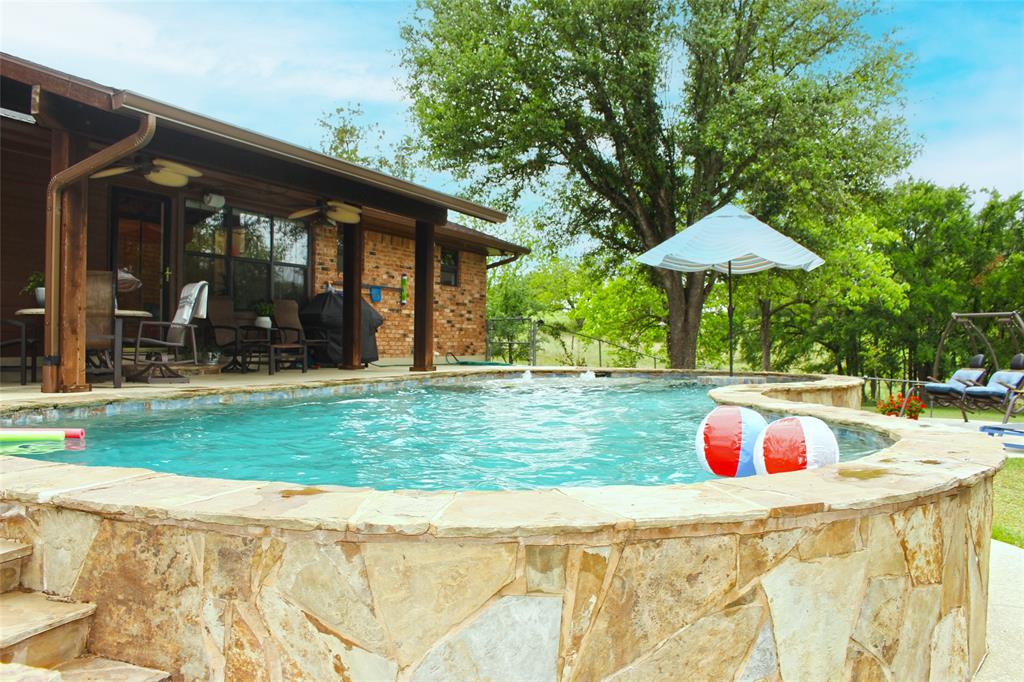 Discover this stunning 3-bedroom, 2-bath home featuring a spacious open floor plan and an inviting pool. Located along a beautiful Bosque  riverfront, the property offers direct access via concrete steps—ideal for fishing and kayaking enthusiasts. Surrounded by mature pecan, pear, and pomegranate trees, along with native mustang grapes, it creates a vibrant, natural setting that attracts deer and local wildlife. Nights here are truly special, with breathtaking starry skies.