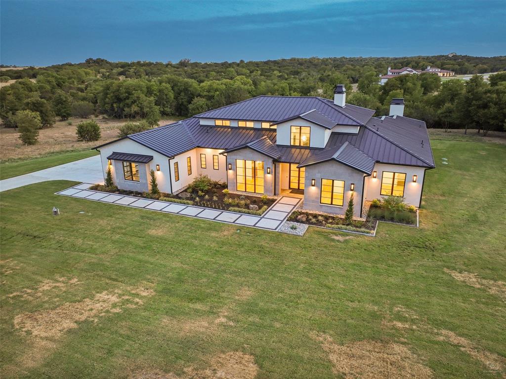 This new construction gem, located in Rancho Ladera, has 5,100 sqft and sits on a sprawling 2.5-acre estate. The quality construction of this 4-bed, 4.5-bath home with 3 living areas impresses. Foam encapsulated with an 11-ton, 18-seer HVAC system, beautiful Marvin windows and doors, and a standing-seam roof enable optimal climate control. Functional features include a 1,000-gallon buried propane tank, a 320-ft deep 17 GPM well, and pre-wiring for a generator. Additional special features include Wolf, Subzero, and Miele appliances, an Isokern fireplace, solid core doors, Emtek hardware, and Walston Barn Doors, full-view garage doors, Visual Comfort lighting, and Infratech flush-mount heaters. The outdoor living area also has a fabulous Isokern fireplace, and every grill master’s dream kitchen, including a Coyote refrigerator, griddle, grill, Big Green Egg, sink, trash, and storage areas.  A pool can be built in 8 weeks.
Come see this fabulous home built by Chad Glasgow in Aledo ISD