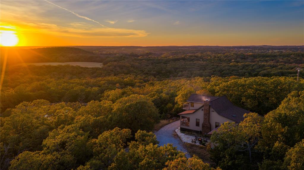 Red Hill Ranch is a turnkey 230± acre retreat within convenient reach of Dallas, Southlake, Westlake, Argyle & Fort Worth - offering the rare opportunity to own substantial acreage this close to the Metroplex. A property meant to be enjoyed & stewarded for years to come, the ranch combines accessibility, privacy, and natural beauty in a setting defined by elevation, water & mature hardwoods. Close enough for frequent use yet private enough to feel removed from the pace of the city, this is the ranch where you can leave the office at 3:30 & drive through your ranch gate by 4:30 on a Friday. The well-maintained residence sits on one of the higher points of the ranch offering panoramic views & a comfortable environment for weekends or extended stays. There is an additional prime building location at an even higher point for another residence. The 6,000± square-foot steel barn, perimeter & cross-fencing, working pens, & ag exemption create a property that is functional from day one. This ranch offers rare topography for a region known for open, flat terrain. With approximately 110’ of elevation change, the terrain moves naturally from mature hardwood groves & improved pasture to prominent high points with long-range views. Surface water includes 4 ponds, the largest over 3 acres & stocked, & several seasonal creeks. The ranch also borders Corps of Engineers land connecting directly to Lake Ray Roberts, creating an expanded wildlife corridor with healthy populations of whitetail deer, turkey, hogs, duck & dove. The balance of topography, water, pasture & hardwoods creates a ranch that lives larger than many properties twice its size. In addition to immediate enjoyment, the property holds long-term strategic value. With approximately 1.75 miles of county road frontage and access to county water, Red Hill Ranch offers flexibility as growth continues moving north.  MUST SEE VIDEO! *Inquire how this property could provide up to $1.65M in potential tax benefits.*