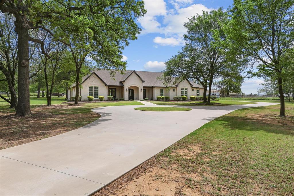 Video walkthrough available on YouTube by searching the property address. Experience the perfect blend of luxury, space, and serene country living in this stunning custom home set on 2.5 picturesque acres. Built in 2020 and offering 3,300 square feet, this exceptional property combines modern design with timeless craftsmanship, creating a warm yet sophisticated retreat you’ll love coming home to. This thoughtfully designed residence features 4 spacious bedrooms and 3.5 bathrooms, with a functional layout and generous room sizes throughout. Step inside to soaring ceilings, beautiful exposed wooden beams, and a striking brick fireplace with gas logs that anchors the main living area. The home is filled with incredible natural light, highlighted by a wall of front-facing doors and abundant windows throughout.

The chef’s kitchen is designed for both style and function, featuring stainless steel KitchenAid appliances, granite countertops, a custom pantry, butler’s pantry, and beautiful wood accents on the vent hood and island. Rich oak hardwood flooring runs throughout the main living areas, complemented by custom tile in all wet spaces.

The luxurious primary suite offers a private retreat with large windows, plantation shutters, and a spa-inspired ensuite bath complete with a standalone soaking tub and an oversized walk-in closet. All additional bedrooms are generously sized with ample storage and high ceilings throughout.

Enjoy outdoor living on the oversized back porch with vaulted wood ceilings, perfect for relaxing or entertaining while taking in the beauty of mature oak trees surrounding the property.

Additional highlights include a 3-car garage and a spacious utility room with sink, extra storage, room for a secondary refrigerator, and a folding counter.

No HOA. This home offers the perfect combination of modern luxury, comfort, and peaceful acreage living.