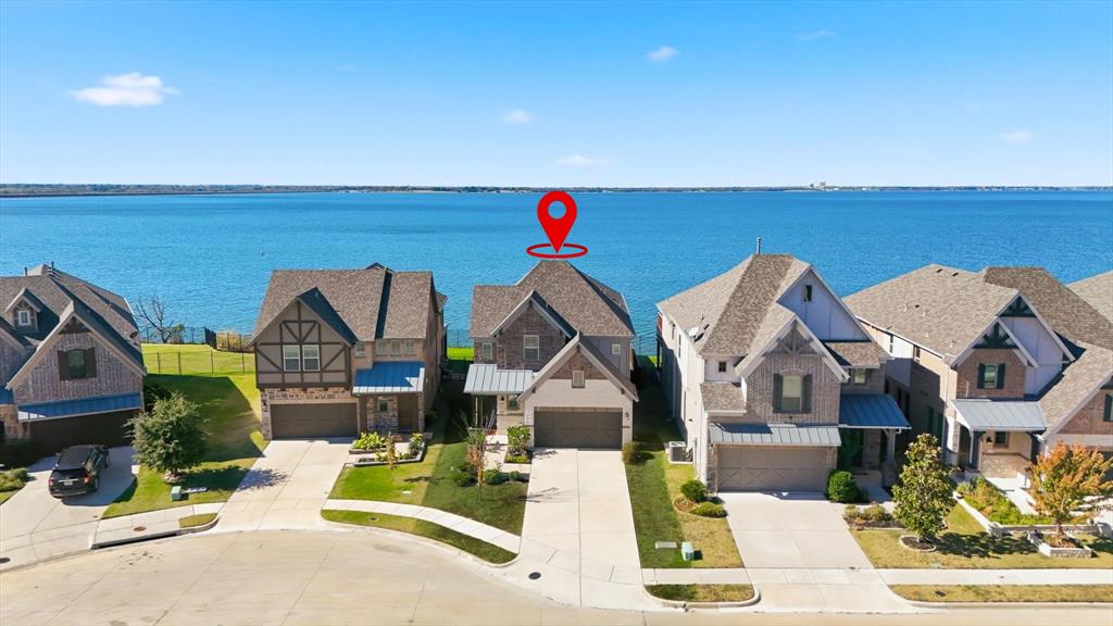 Welcome to 18140 Lakefront Court, your private lakeside sanctuary on the tranquil shores of Lake Ray Hubbard in Forney, Texas. This stunning two-story modern home offers 4 bedrooms, 4.5 bathrooms, and over 3,200 sq ft of beautifully designed living space. Built in 2020 and perfectly positioned in the sought-after Travis Ranch Marina community, this property captures breathtaking panoramic lake views from nearly every room. Step inside and experience open-concept living with soaring ceilings, elegant finishes, and seamless indoor-outdoor flow. The gourmet kitchen features quartz countertops, custom cabinetry, and stainless steel appliances — opening to a spacious living area that overlooks the water through expansive picture windows. The primary suite, thoughtfully located on the main floor, offers a peaceful retreat with serene lake views, a spa-style ensuite bath, and a generous walk-in closet. Upstairs you’ll find three large guest rooms, each with unique character, plus a versatile loft-style game room and balcony perfect for entertaining or simply watching the sunset. Enjoy mornings with coffee on the covered patio or evenings spent under the stars by the lake. The oversized backyard provides endless potential for outdoor living — imagine adding a pool, fire pit, or private dock for direct lake access. With a two-car garage, extended driveway, and premium location just 25 minutes from Downtown Dallas, this home perfectly blends luxury, comfort, and convenience. Rarely do true lakefront properties like this become available — experience lake living at its finest and make 18140 Lakefront Court your forever home today.