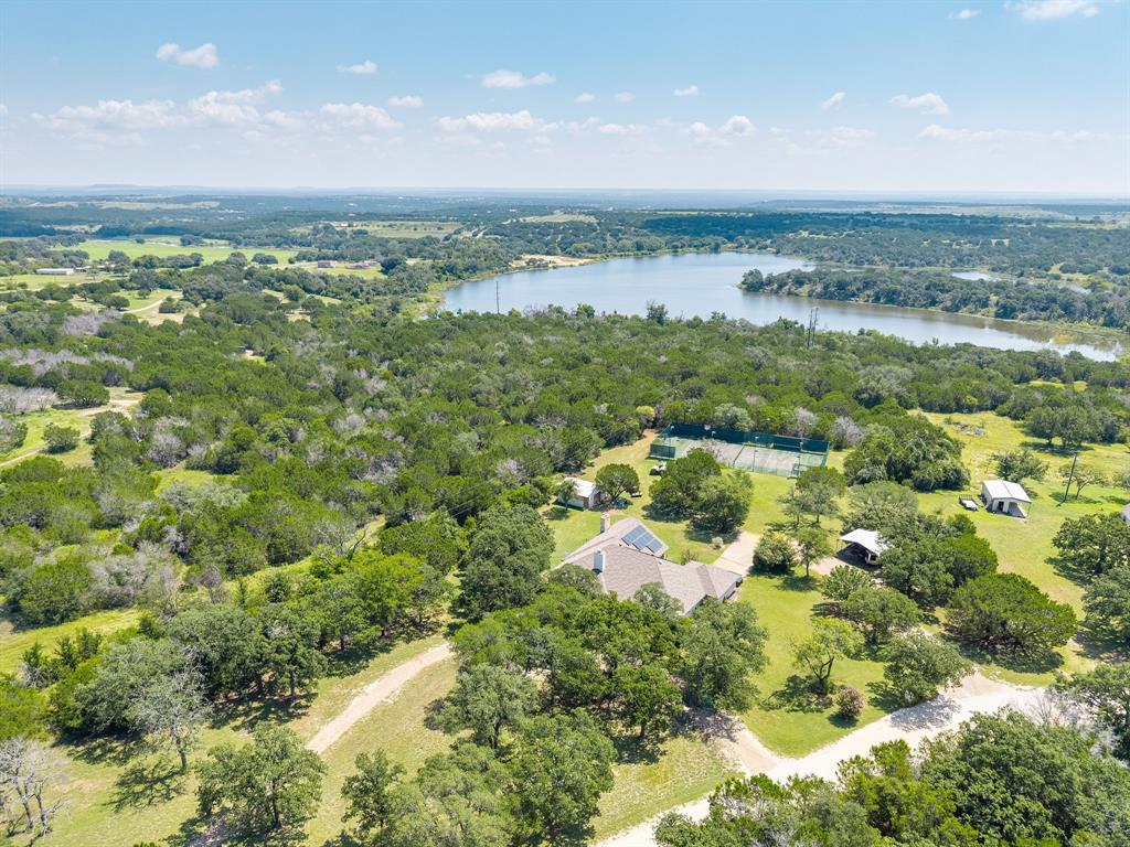 Experience the perfect blend of space, style, and serenity with this stunning 10-acre retreat just outside Hamilton, TX. The impressive 3,300 sq. ft. brick home offers 3 spacious bedrooms, as well as fourth space that can utilized as a bedroom or family room, and 3.5 baths, designed for both comfort and entertaining. The inviting living room features a cozy wood-burning fireplace and flows seamlessly into a bright breakfast nook and gourmet kitchen with granite countertops, stainless steel appliances, and a center island. Enjoy elegant meals in the formal dining room and appreciate the convenience of a large utility room and generous storage throughout. The primary suite is a true escape with a soaking tub, separate shower, split vanities, and rich granite finishes. Natural light pours through expansive windows, highlighting every detail. Step outside to your private oasis—an oversized covered patio with a wood-burning fireplace, built-in grill, and ceiling fans sets the stage for unforgettable gatherings. Play a match on your private tennis court, relax under the canopy of mature trees, or take in the peaceful views of the neighboring city lake. Complete with a carport and storage shed, this property is a rare combination of luxury, recreation, and tranquility.