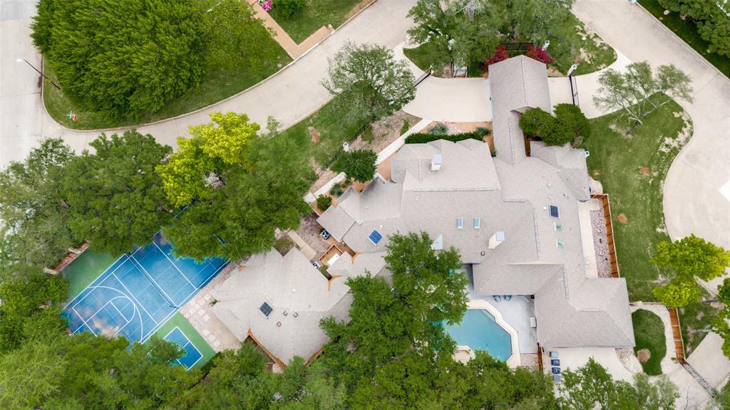 Set behind a gated drive on an oversized .89-acre lot in coveted Bent Tree North, this exceptional single-story estate offers 5 bedrooms, 4 full baths, 2 half baths, and 5,944 square feet of thoughtfully designed living space. Expansive living and entertaining areas feature soaring ceilings, abundant natural light, and seamless indoor-outdoor flow. The chef's kitchen opens to inviting gathering spaces, while walls of windows overlook the resort-style backyard complete with pool, spa, mature landscaping, and a private sport court ideal for pickleball, basketball, and outdoor recreation. The spacious primary suite provides a peaceful retreat, complemented by generously sized secondary bedrooms. A 3-car attached garage, porte-cochere, and circular gated drive enhance both convenience and curb appeal. Rarely does a property offer this combination of single-level living, nearly an acre of land, resort-style amenities, and a premier North Dallas location within Plano ISD.