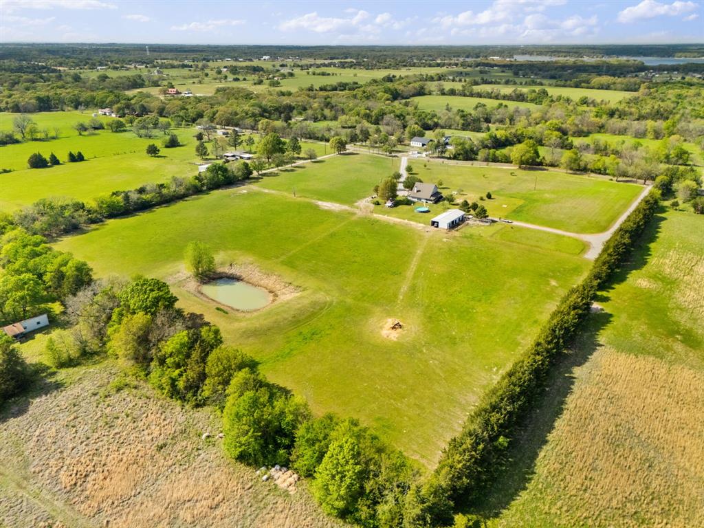 Experience the best of North Texas country living on nearly 18 AG-exempt acres in Bonham, ideally located just minutes from Lake Bonham and Bois D’Arc Lake. This well-appointed two-story farmhouse blends charm, functionality, and wide-open space, perfect for those seeking a private retreat, hobby farm, or recreational use. A classic wrap-around porch with porch swings sets the tone, offering peaceful sunrise and sunset views across rolling acreage. Inside, the home features 5 bedrooms, a dedicated home office, formal dining room, and a spacious eat-in kitchen designed for gathering. The inviting living area is anchored by a wood-burning stove fireplace, adding warmth and character. The land is thoughtfully improved for versatility and rural living. A well-equipped barn includes 4 livestock stalls, plus a large chicken coop or optional 5th stall, complete with roll-up doors, fans, LED lighting, and additional storage. Fenced pastures and a seasonal pond provide ideal conditions for livestock, horses, animal grazing rotations, or recreational use. Additional outdoor features include an above-ground pool for warm Texas summers and a separate dog house with a window unit, doggy door, and fenced run, perfect for pet lovers. Whether you’re envisioning a lake-adjacent estate, executive getaway, recreational retreat, equine therapy, or even future development with large lots, this property offers exceptional potential. With AG exemption in place - keeping property taxes lower, usable acreage, mature trees, abundant wildlife, and the peaceful setting close in proximity to two of North Texas’ premier lakes, this property offers a rare opportunity to enjoy space, privacy, and lifestyle without sacrificing convenience. See Transaction Desk for survey, upgrades, and additional property details.