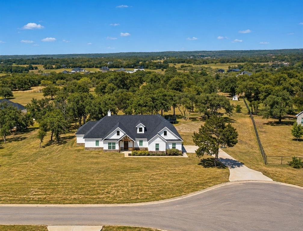 Tucked away toward the end of a quiet CUL-DE-SAC in AVIARA RIDGE, this modern Farmhouse sits on 2.227 acres in the highly sought-after PEASTER ISD. With an OPEN LAYOUT, this 4 Bed, 3.5 Bath home offers a functional design, where all 3 secondary bedrooms are thoughtfully arranged around a central GAMEROOM (or 2nd Living Area)- creating the perfect space for gathering, relaxing, and entertaining. A TWO-SIDED GAS FIREPLACE creates a striking focal point, connecting the main Living Area and Gameroom, while a WALL OF WINDOWS in the spacious Living Area showcases the LARGE, SCENIC BACKYARD that features MATURE TREES and sometimes even spottings of wildlife. The heart of the home is the stunning Farmhouse-style kitchen, thoughtfully equipped wtih a GAS COOKTOP, DOUBLE OVEN, ICE MAKER, POT FILLER AND FARM SINK, making this kitchen both stylish and highly funtional. Enjoy the PRIVACY and SPACE that country living has to offer- all while being less than 15 miles from downtown Weatherford. The Ric Williamson loop also makes for an easy commute to the metroplex! 309 Aviara Ct. is a MUST SEE!