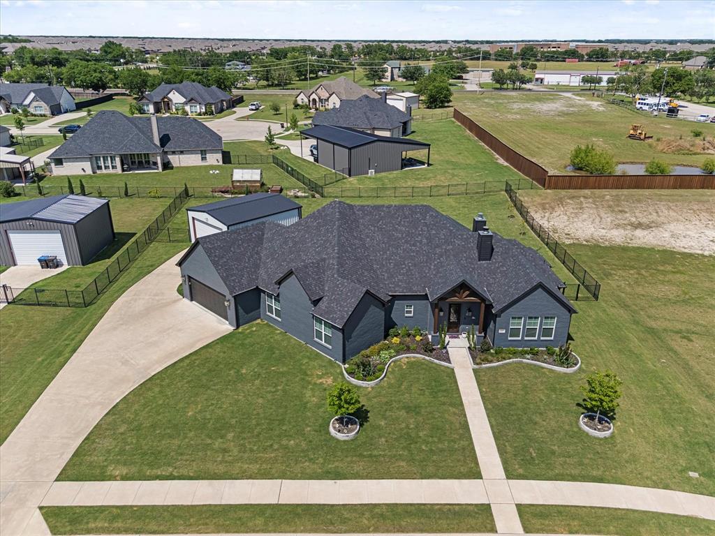 Welcome to your expansive single-story town & country retreat—a residence that seamlessly blends comfort, functionality, & entertainment. Situated in a serene rural setting, near great schools, this home offers the tranquility of countryside living while maintaining convenient access to major highways & nearby cities. Step inside to discover an open-concept great room adorned with a cozy fireplace creating an inviting atmosphere for both relaxation & gatherings. Gourmet kitchen is a culinary enthusiast's dream, featuring a substantial island, a 5-burner cooktop with a convenient pot filler, & seamless flow into the adjacent dining area—perfect for hosting family & friends. Adjacent to the kitchen, the media room offers a versatile space ideal for a play area or an ultimate man cave experience, complete with custom built-ins to house your entertainment essentials. Work from home in his or her offices. The Primary Suite serves as a private sanctuary, boasting custom built-in dressers in both his & her closets, & a luxurious bathroom equipped with an oversized shower featuring dual showerheads. Designed with both style and practicality in mind, this home includes privacy curtains throughout & a second fireplace located on the outdoor patio—perfect for enjoying cool Texas evenings. The fully fenced backyard is a haven for relaxation & recreation, showcasing a sparkling pool secured with a custom Katchakid net & safety fence, along with a designated area for pool equipment. Car enthusiasts & DIY aficionados will appreciate the attached 3-car tandem garage wired for a 50-amp generator, as well as a separate 22' x 28' garage. This additional space is versatile enough to accommodate two more vehicles, a personal gym, or a workshop, & features epoxy flooring, 2-inch foam insulation, and a split AC heater unit.  Don't miss the opportunity to make this exquisite home your own—a true gem offering the comforts of modern living in a peaceful, community-oriented setting.