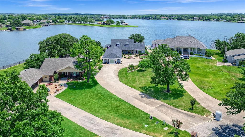 Lakefront living at its very best! Spectacular lake views, a cul-de-sac location a private lot, and close to the front gate. This completely remodeled home exudes elegance and comfort. It's ideal for entertaining with its open floor plan and panoramic views of the lake, a covered deck, an outdoor kitchen-grilling area, a firepit area and a covered boat slip and dock - with 4' depth to the lakebed. 4 bedrooms and 3 baths easily accommodates family and guests. Beautiful landscaping leads you to the entry of this 4288 SF home with its numerous custom touches. The living area opens to the spacious dining room and chef's kitchen leading to the butlers pantry & wine room. The sunroom extends the full width of the back of the house and is perfect for reading, games or quiet conversations. The 1st floor owner's suite has an oversized walk-in closet, extensive custom shelving and a spa-like ensuite bath. There is an additional bedroom and full bath downstairs. The large utility room has a separate storage area, built in cabinetry and lots of counter space.  It's great for crafts and leads directly to the garage. An office, 2 bedrooms, a sitting area (could be 5th bedroom) and a bath are upstairs. Step out the back door onto a covered porch that leads to an outdoor entertaining area that can be configured to your tastes. The dock has 2 slips and a lift. This is a home for all seasons that comfortably embraces a family yet provides an outstanding venue for entertaining. With your own dock,  water activities are literally just feet away.  Watch the spectacular 4th of July fireworks from your own backyard.  Play golf on one of Texas' most popular and well-manicured 18-hole private courses.  Residents play for free, with a reasonable fee for accompanying guests.  Enjoy a challenging game of tennis or pickleball on the east beach.  Relax after an exhausting day of sports or work, and dine at the private lodge. There is just too much to list.  Make an appt & come see for yourself.