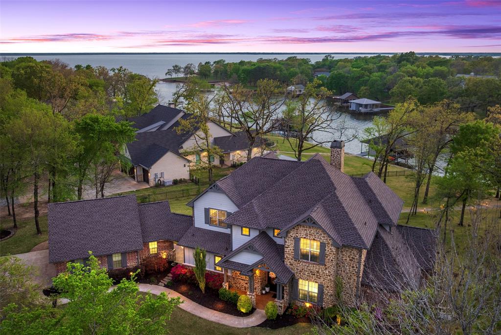 Stunning newly updated lakefront (181 ft of waterfront) estate in the gated Pinnacle Club at Cedar Creek Lake — over 3,800 sq. ft. of timeless transitional farmhouse living on 1.475 acres of mature oaks–and professionally landscaped, fenced grounds. From the moment you arrive the home feels fresh and current with full interior and exterior paint, four new statement chandeliers, updated light fixtures and ceiling fans, new carpeting and refined finishes that elevate the plan for 2026 and beyond.

The water-facing layout welcomes you into a dramatic grand living room with a 26' vaulted ceiling and stone fireplace. The chef’s kitchen features new Carrera quartz countertops and backsplash, cabinet hardware, KitchenAid stainless appliances, pendant lighting over the island and a built-in wine refrigerator. Baths showcase new vanities with quartz and modern fixtures.

Two generous main-level primary suites provide private en-suite retreats — one includes an oversized sitting area, lake views and a balcony. Three upstairs bedrooms (one with a private balcony) plus a game room with dry bar, and balcony offer additional living and water views. Indoor and outdoor living blend effortlessly: living and dining open to a covered terrace and outdoor kitchen — ideal for entertaining while soaking in panoramic water views. Enjoy a waterside wood-burning fire pit just feet from the shoreline — ideal for cool evenings and sunset gatherings.

Exterior highlights include an oversized two-car garage plus a dedicated golf-cart garage and a boatdock with boat slip, jet-ski lift and an upper viewing deck overlooking the channel and open water. Pinnacle Club life surrounds you with an 18-hole championship golf course and community amenities including a full-service restaurant, pool, tennis, pickleball, basketball and playground.

Exceptionally move-in ready — a beautiful, timeless lakefront escape built for entertaining and everyday living.