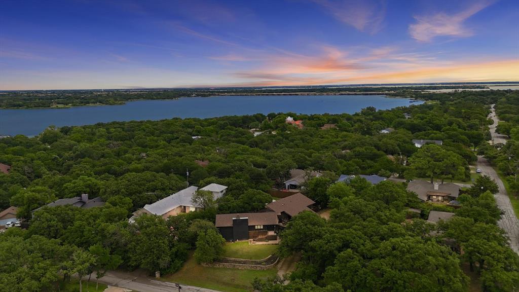 Tucked into one of Highland Village's most cherished pockets, this one-of-a-kind retreat offers a lifestyle that's increasingly difficult to find. Surrounded by rolling hills, towering trees, and custom homes full of character, this peaceful enclave feels more like a getaway than a suburban neighborhood. Spend your mornings meandering down a peaceful walking trail or taking a short stroll to the lake to watch breathtaking sunrises and sunsets over the water.

Designed for those who crave something beyond the ordinary, this curated and inviting home blends warmth, charm, and flexibility. The heart of the home is an expansive open-concept living space that effortlessly adapts to your lifestyle—whether hosting gatherings, creating cozy conversation areas, or simply enjoying everyday living. With three bedrooms plus a private office featuring its own exterior entrance, the floor plan offers exceptional versatility for working from home, or meeting clients.

Unlike today's cookie-cutter construction, this home embraces individuality and endless possibilities. An unfinished basement level presents a rare opportunity to nearly double the home's living space, creating anything from a private owner's retreat to a game room, private garage or multi-generational living.

Outside, the experience continues. A wraparound deck invites you to relax among the treetops and soak in the views, while the spacious backyard offers room to play, entertain, or simply enjoy the serenity of nature. Featuring an oversized driveway and carport, you'll enjoy space for an RV, boat, or lake toys, fantastic storage—and no HOA restrictions on nearly a half an acre lot.

Beyond its exceptional design, the home offers practical value as well, with both AC units recently replaced—an important investment that provides peace of mind for years to come.

For buyers seeking privacy, nature, character, and the opportunity to create something special, this gem is unlike anything else on the market.